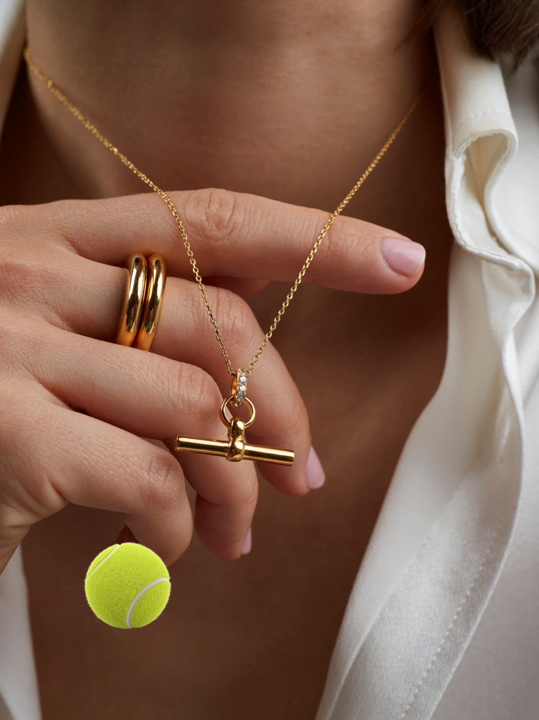 Gold T-bar necklace with small jeweled charm on a trace chain