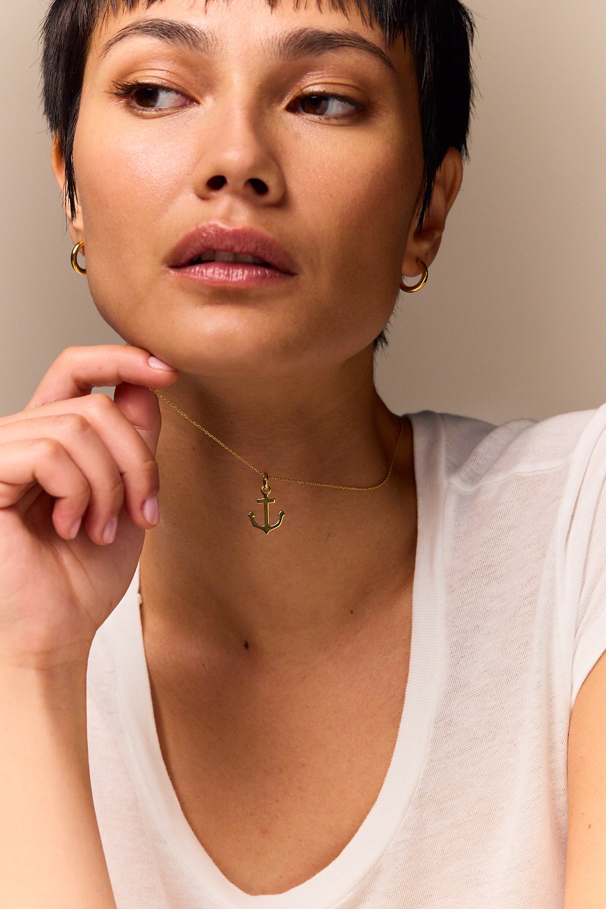 Gold anchor pendant necklace with trace chain, worn at collar