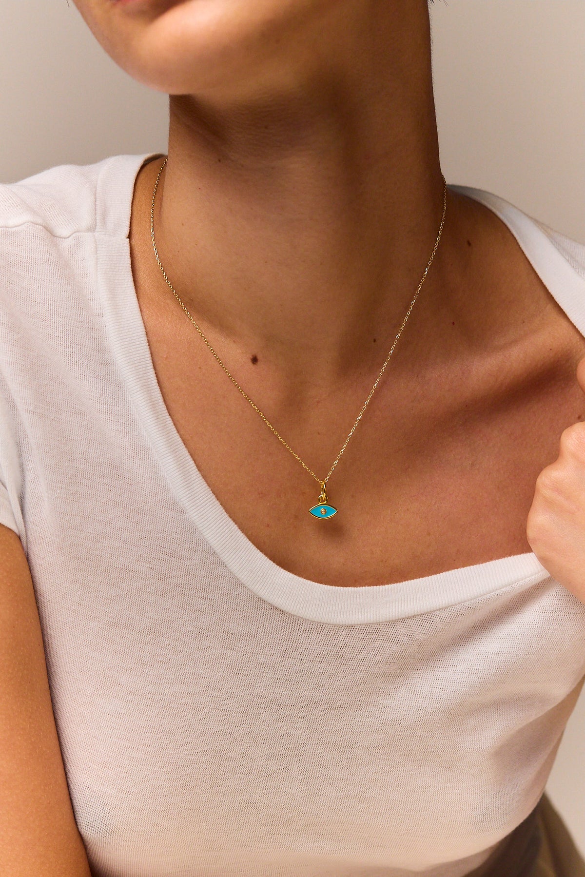 Gold-tone trace chain necklace with turquoise evil eye pendant on neckline