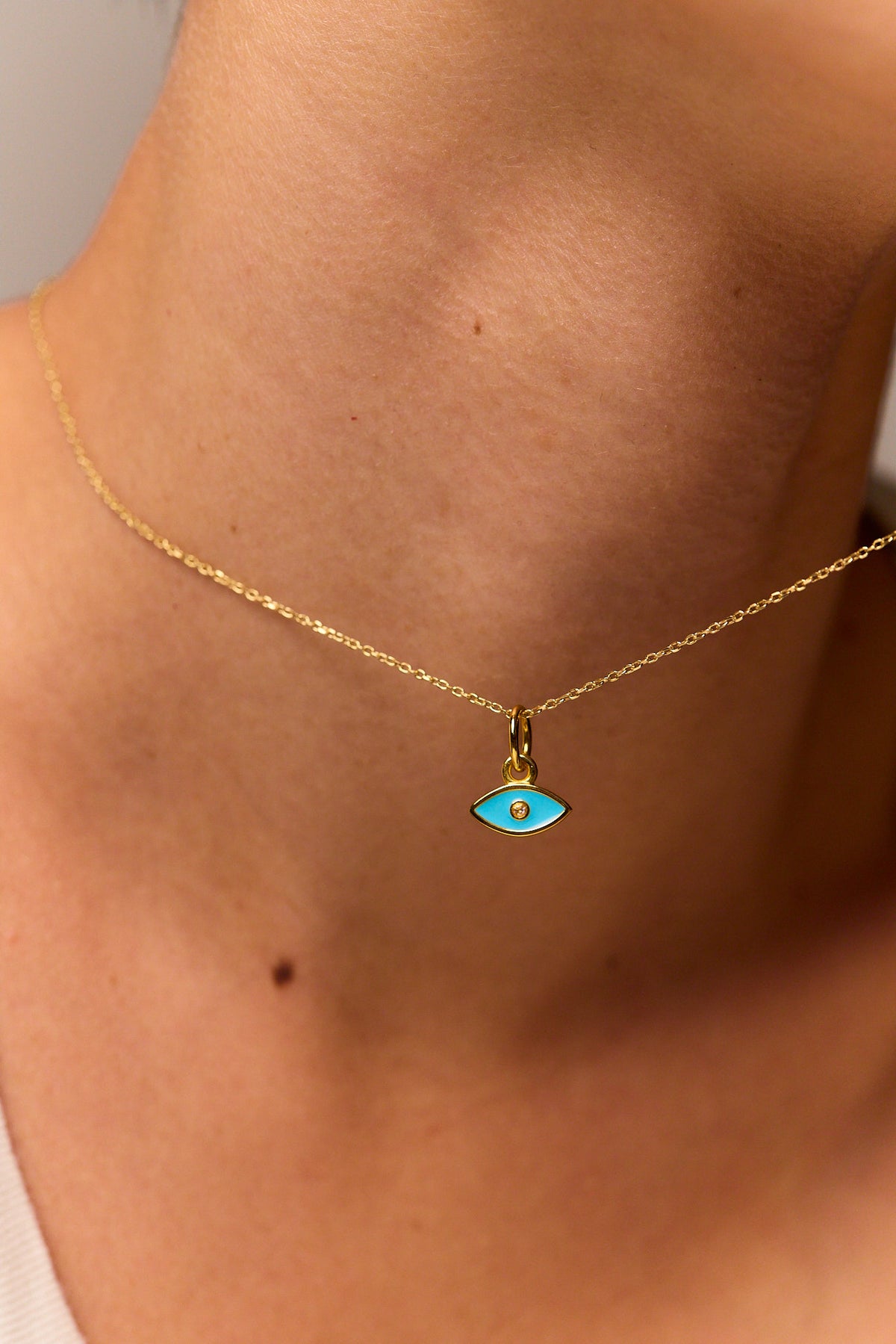 Close-up gold-tone trace chain with turquoise evil eye pendant