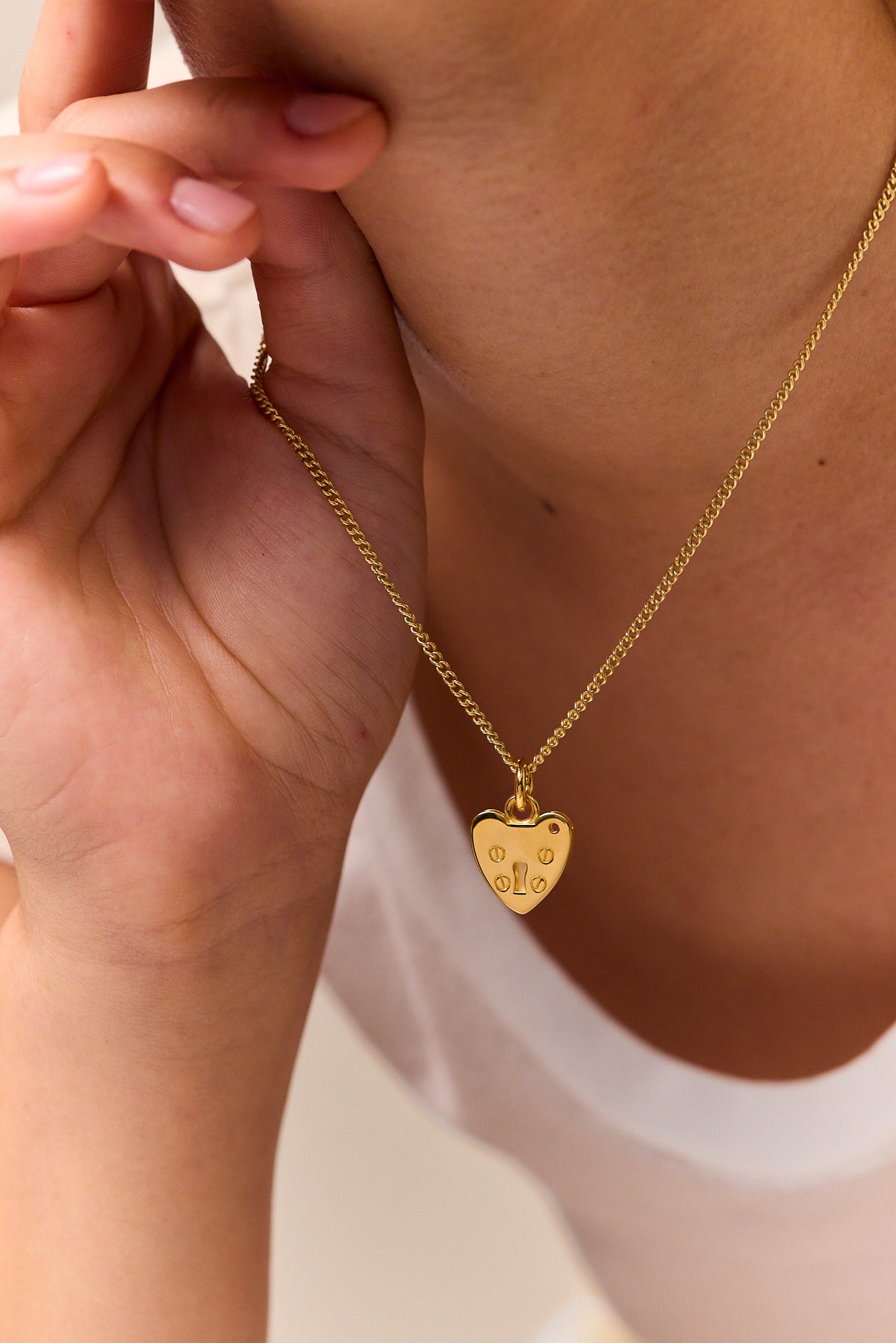 Gold heart padlock charm necklace detail held by hand