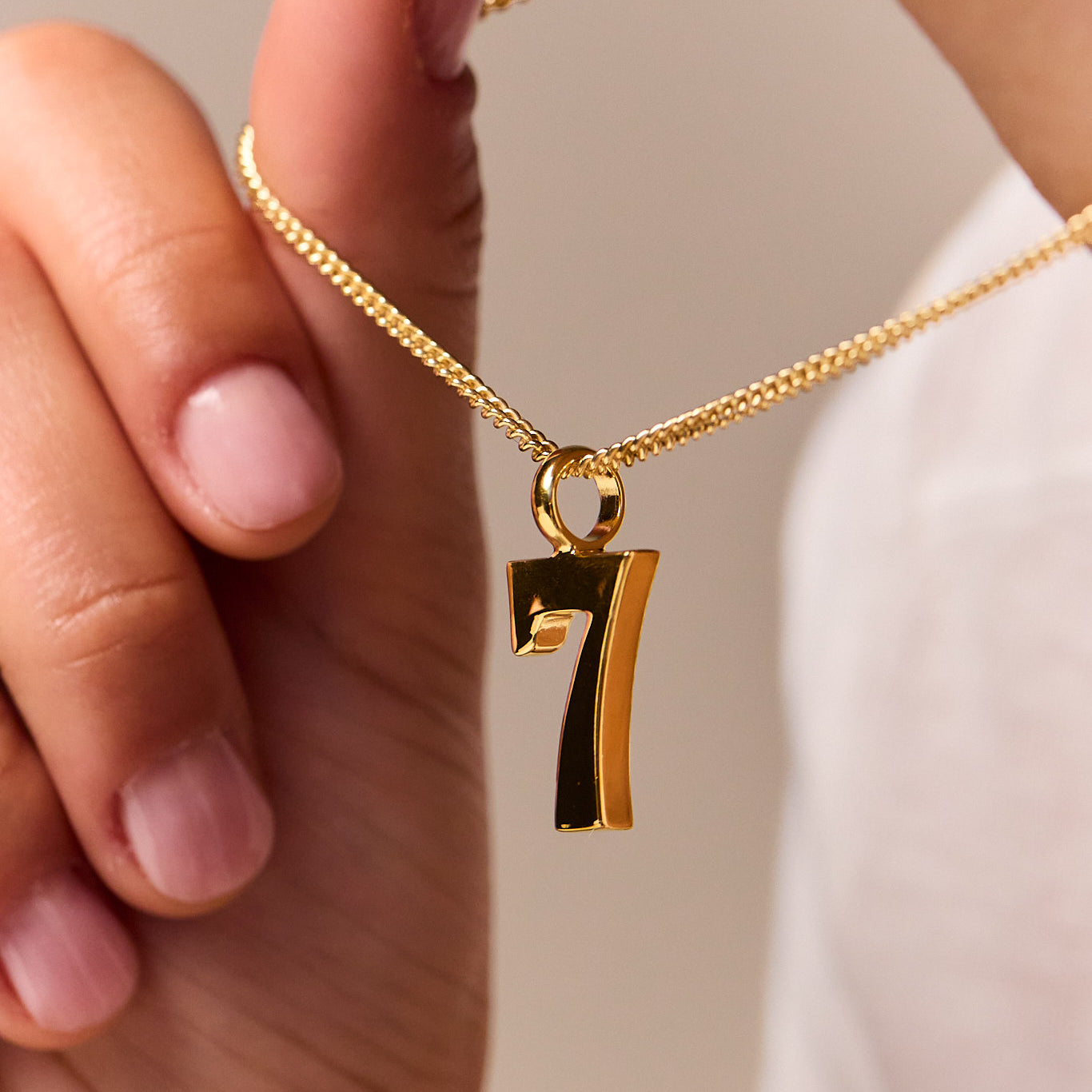 Gold curb-chain necklace with No 7 pendant and round connector link.