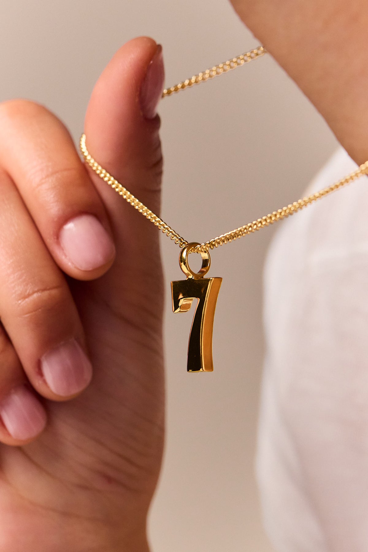 Gold curb-chain necklace with No 7 pendant and round connector link.