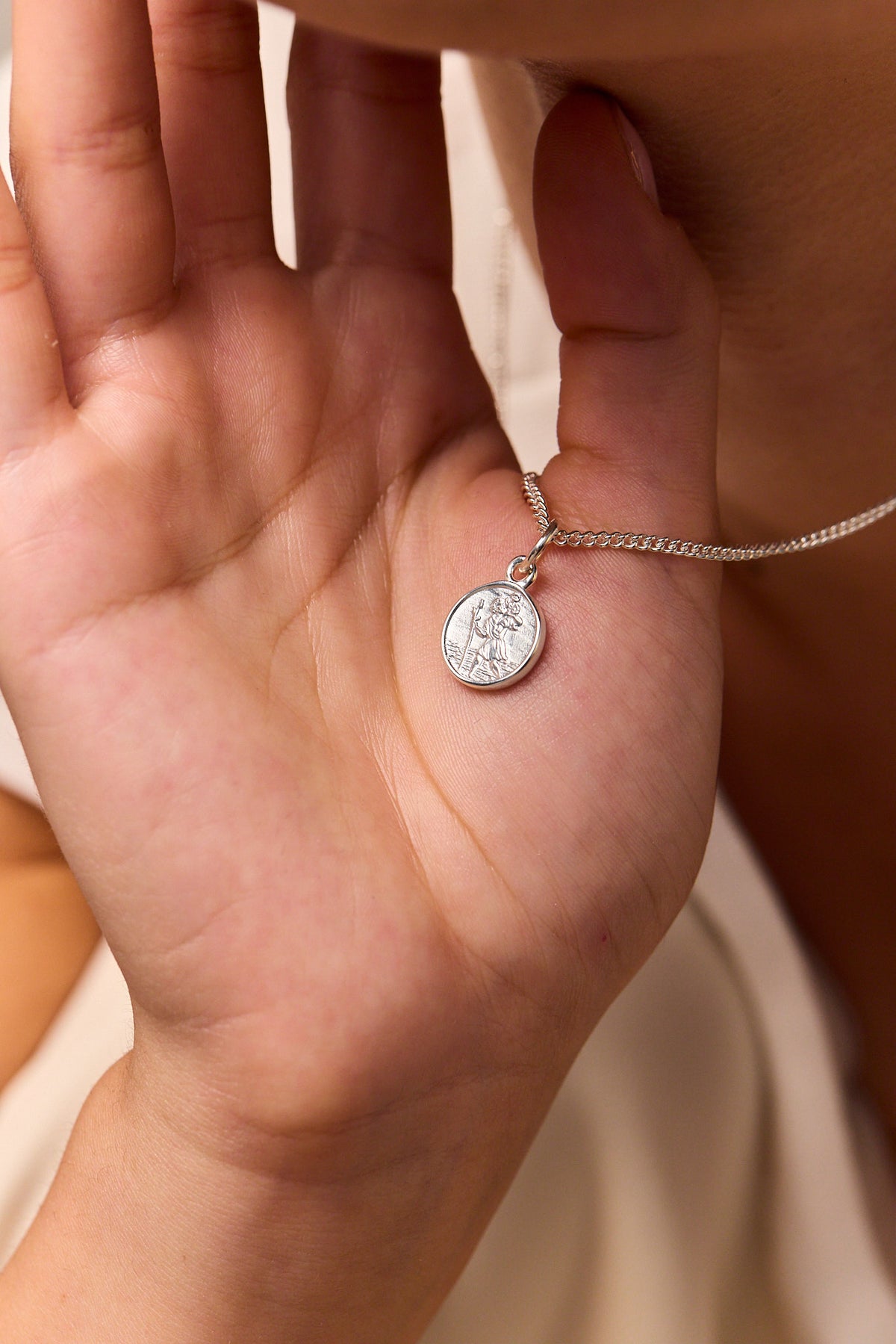 Sterling silver St Christopher medallion pendant on fine curb chain, shown in hand