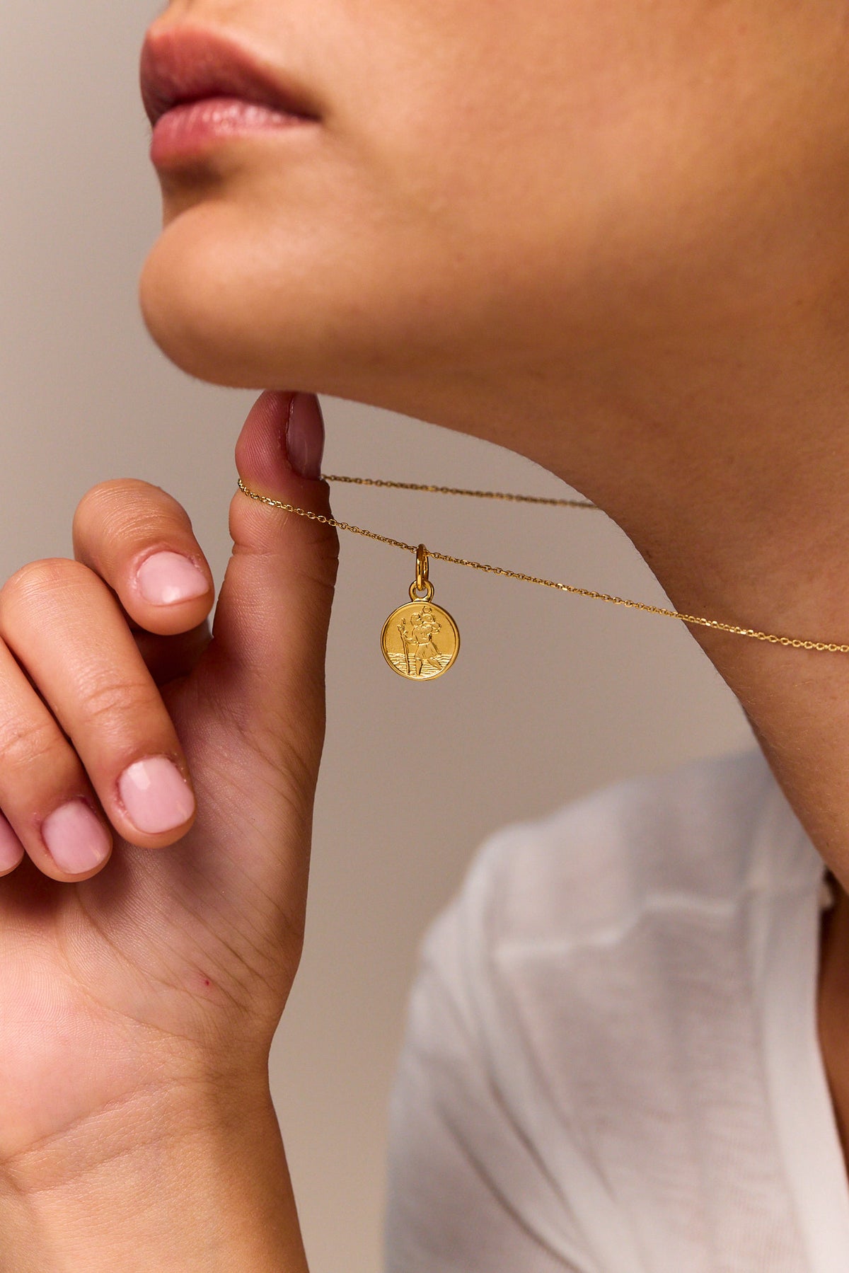Gold trace chain necklace with round St Christopher charm pendant near the neck