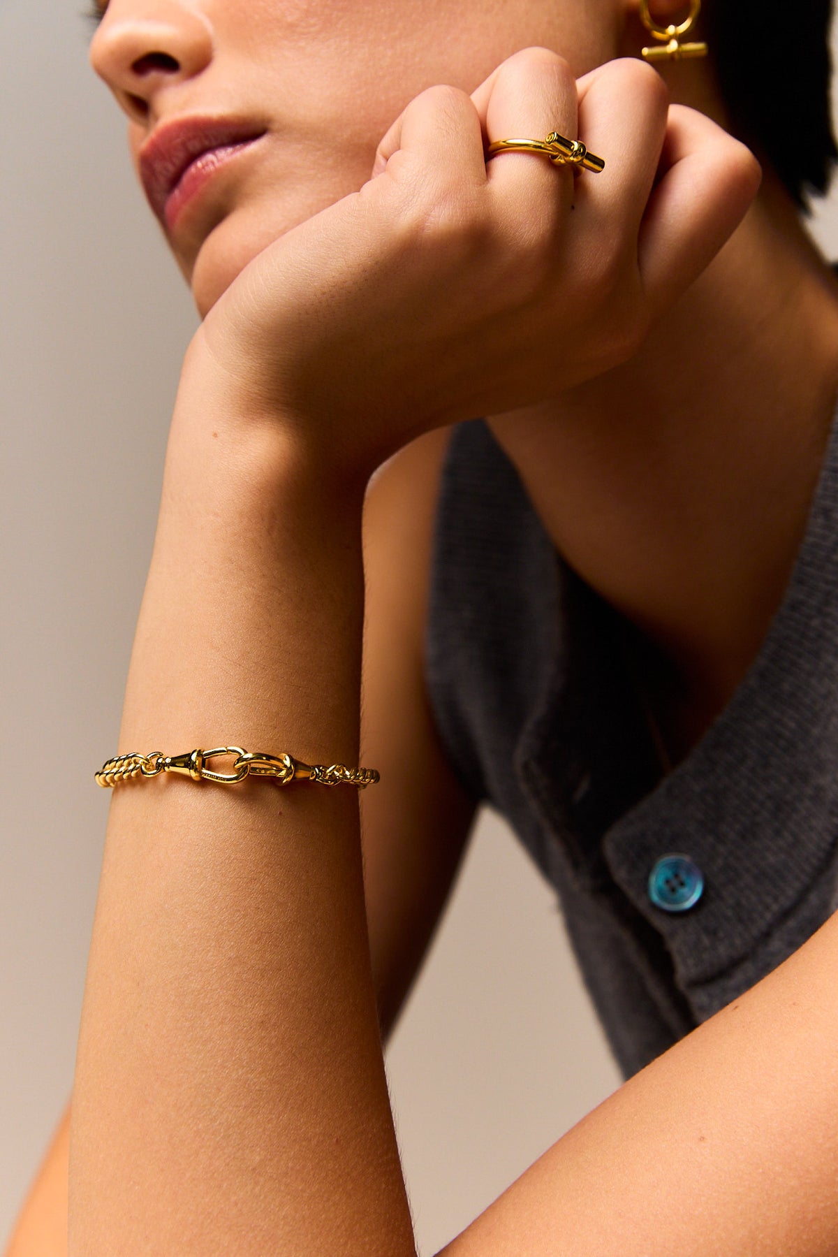Slim gold curb bracelet worn on the wrist with a lobster clasp