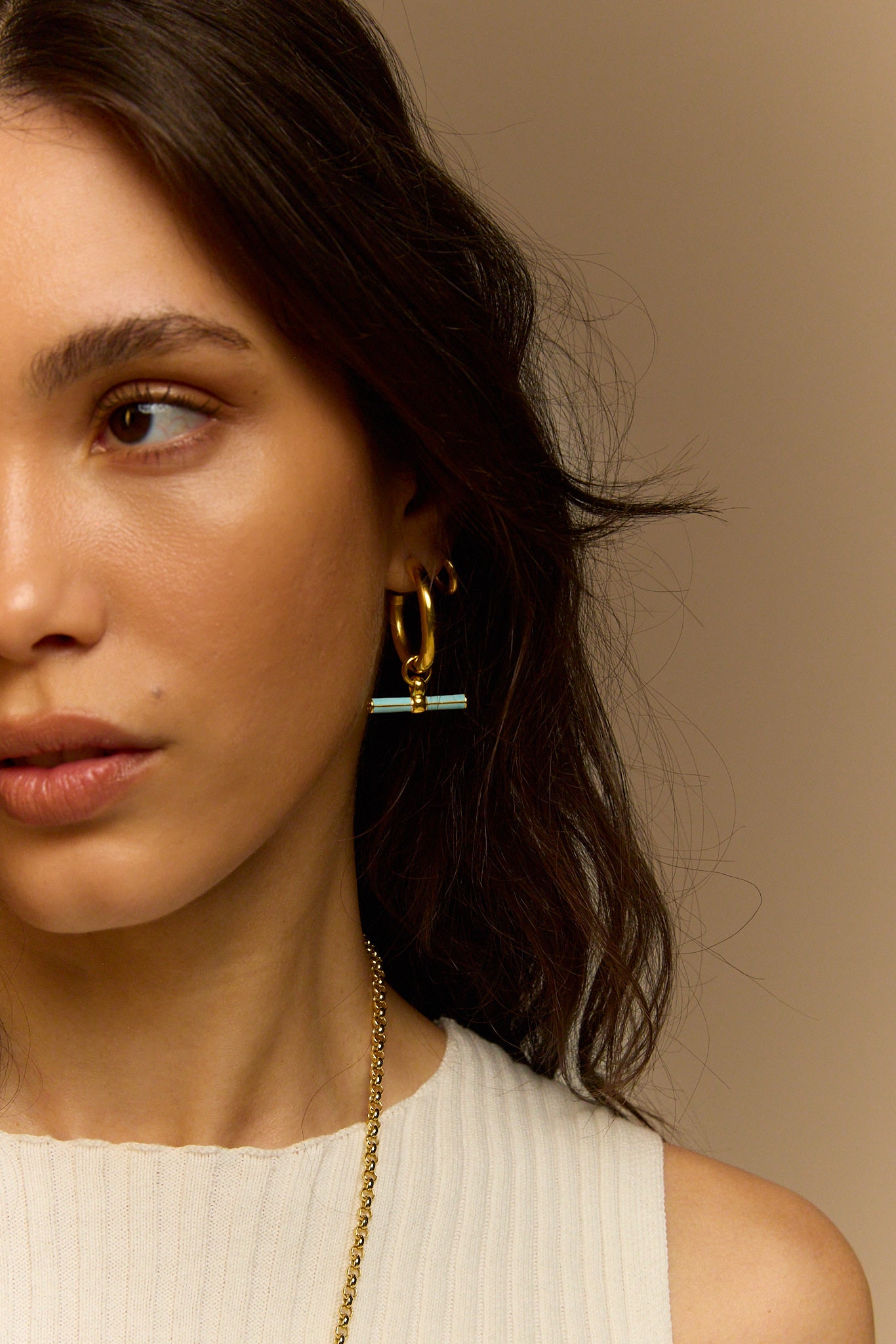 Gold hoop earrings with blue enamel bar and T-bar charm on model