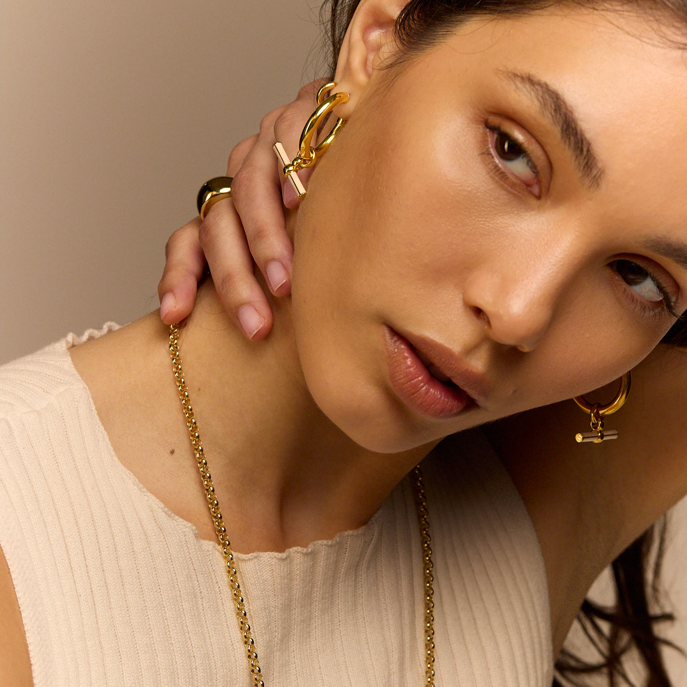 Gold-tone hoop earrings with cream enamel T-bar dangle on model