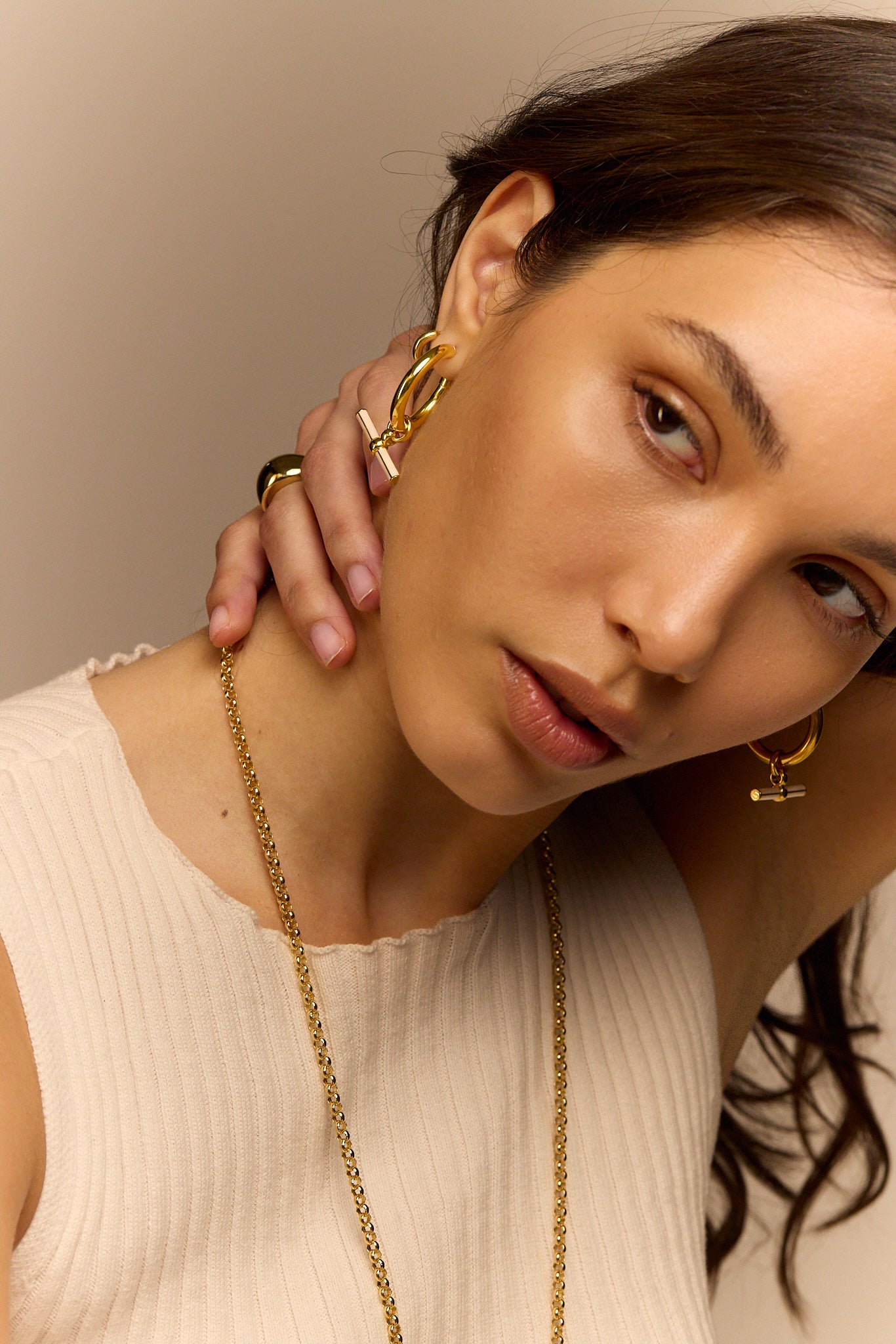 Gold-tone hoop earrings with cream enamel T-bar dangle on model
