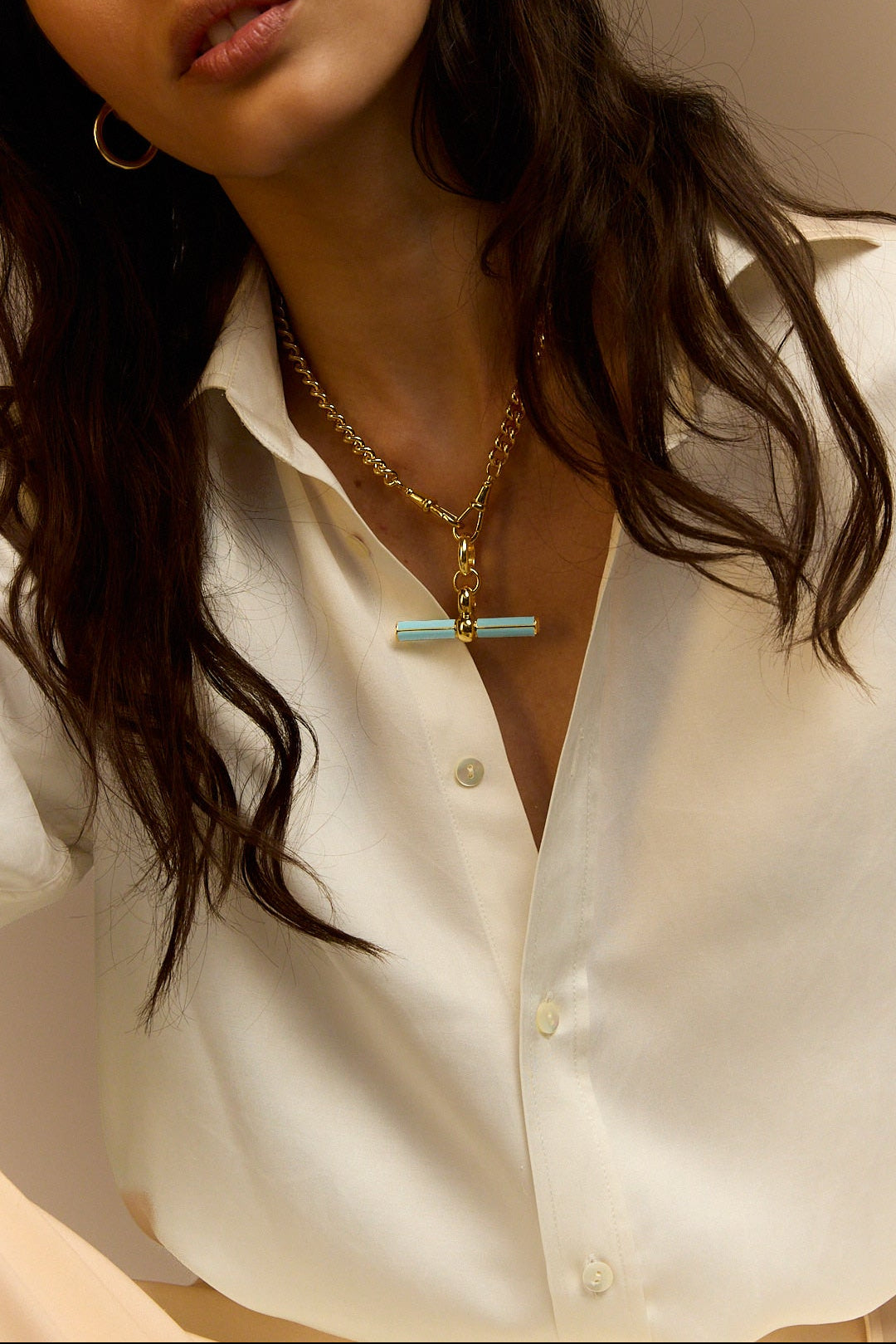 Gold curb-link necklace with blue enamel T-bar charm at neckline