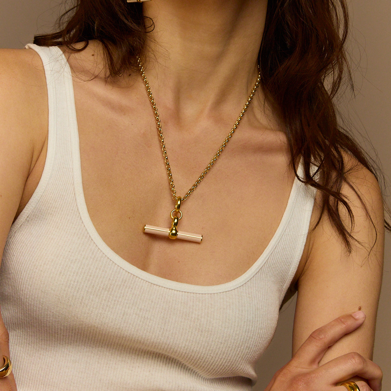 Close-up gold necklace with cream enamel T-bar pendant on chunky chain