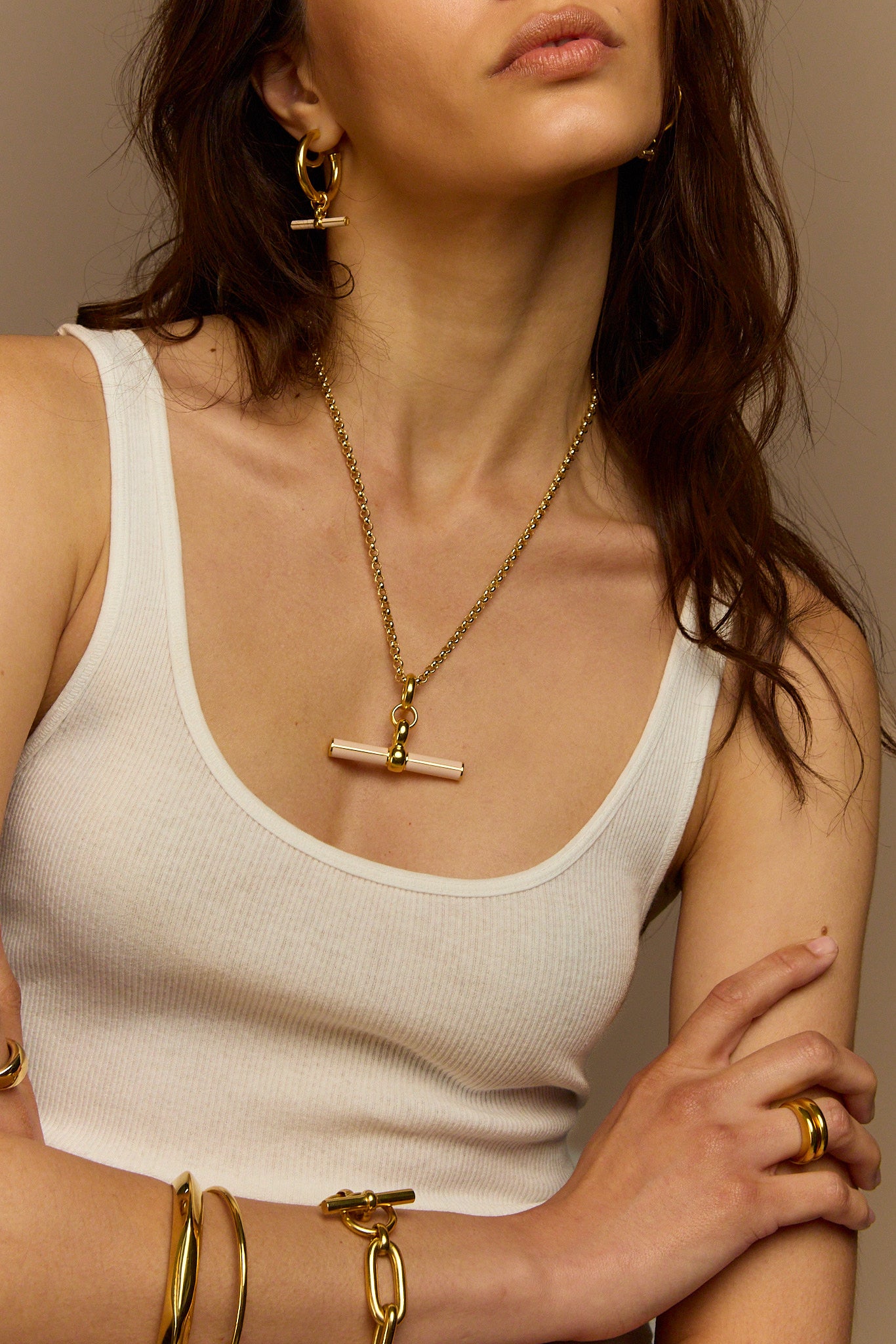 Close-up gold necklace with cream enamel T-bar pendant on chunky chain