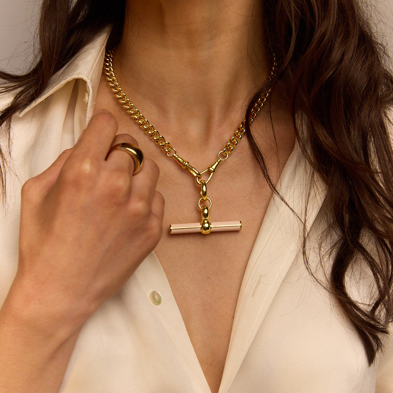 Gold curb chain necklace with cream enamel T-bar pendant, close-up
