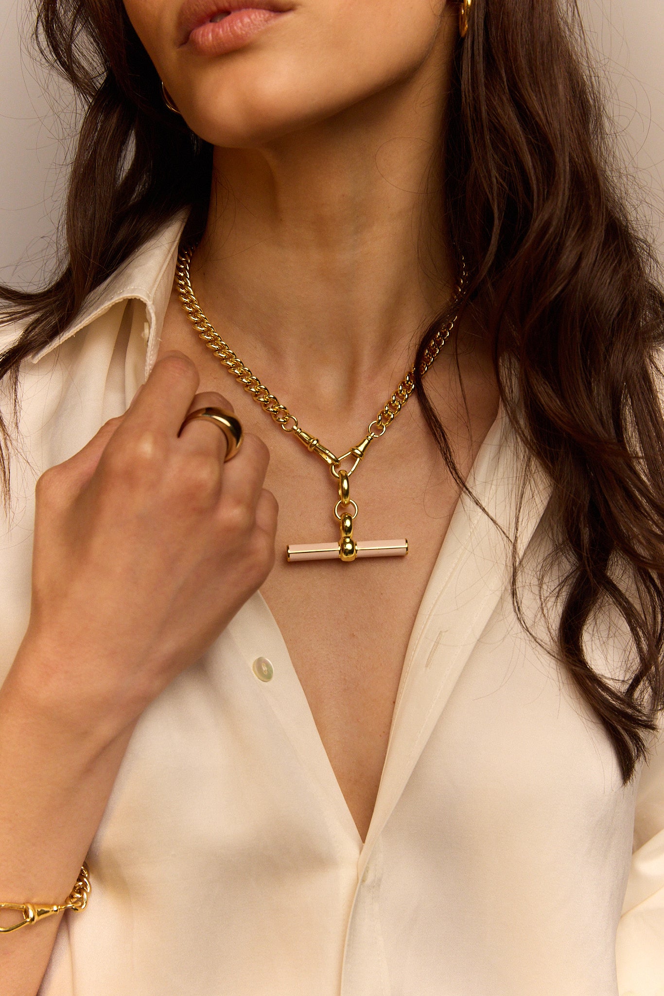 Gold curb-link necklace with cream enamel T-bar pendant close-up