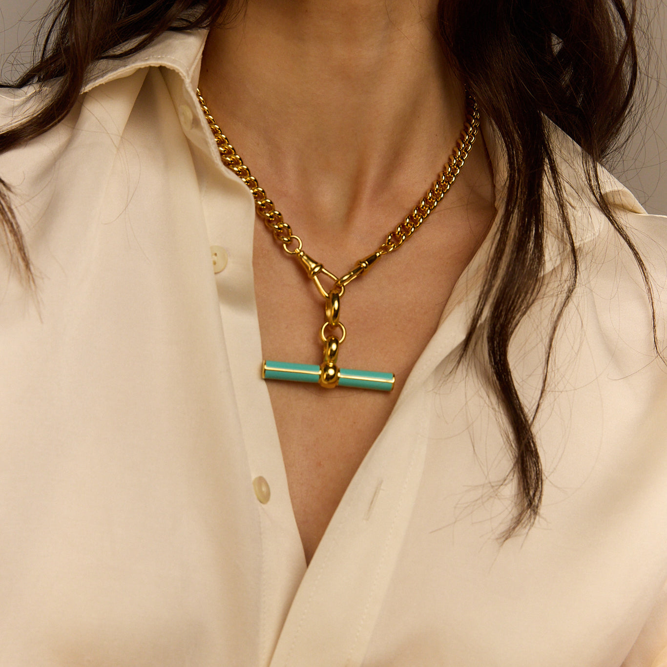 Mint enamel T-bar pendant on gold chain necklace at chest close-up