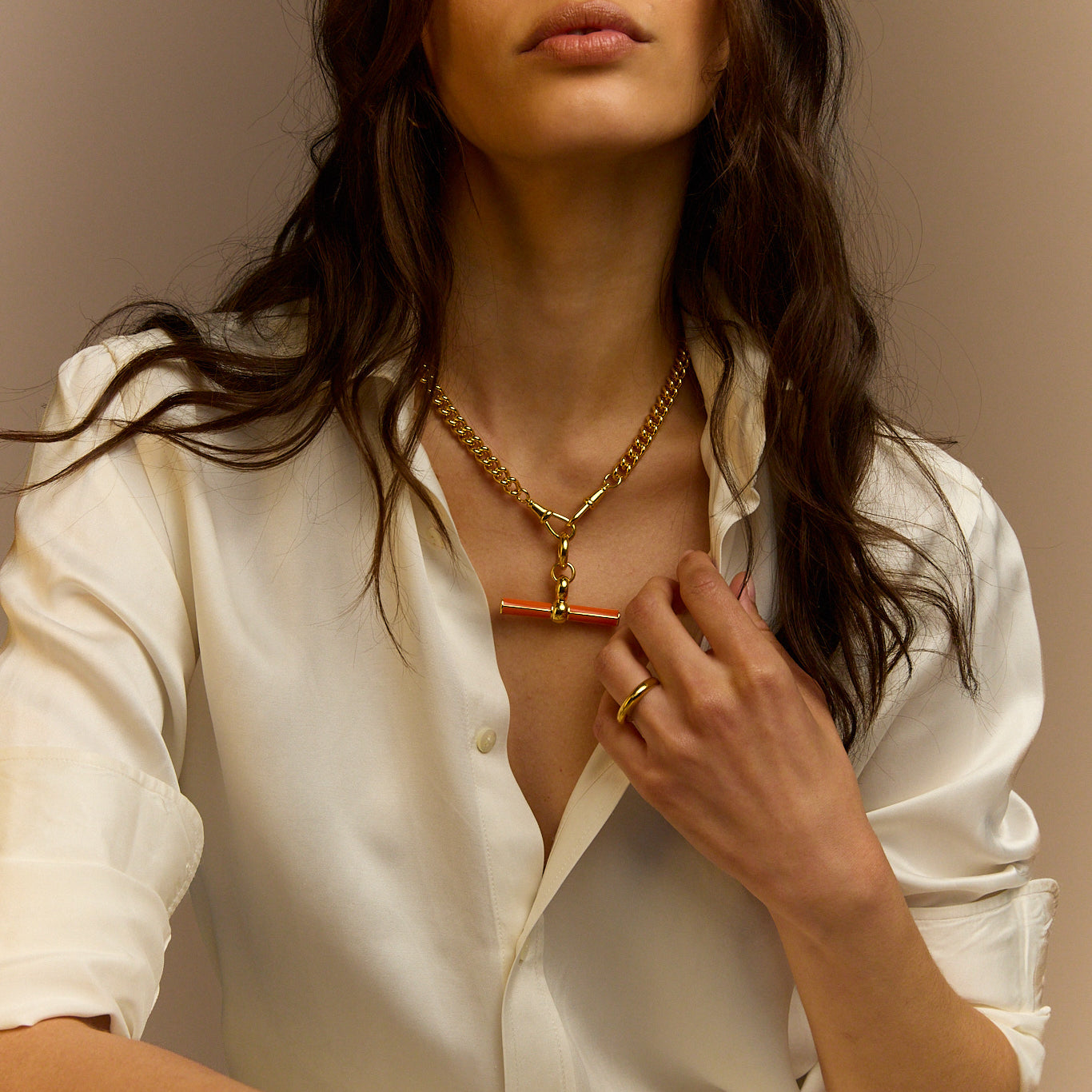 Gold chain necklace with orange enamel T-bar pendant, model styling close-up