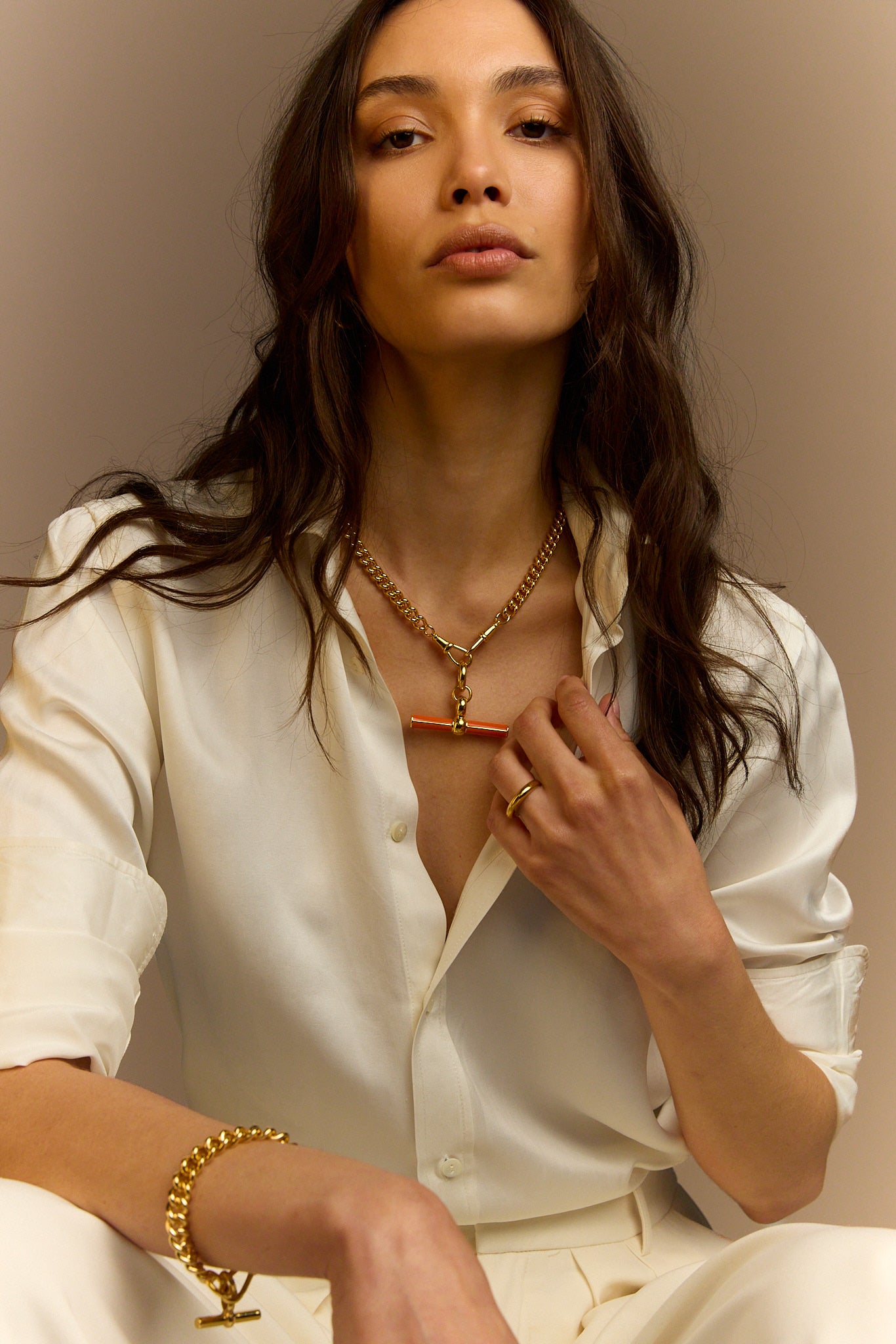 Gold chain necklace with orange enamel T-bar pendant, model styling close-up