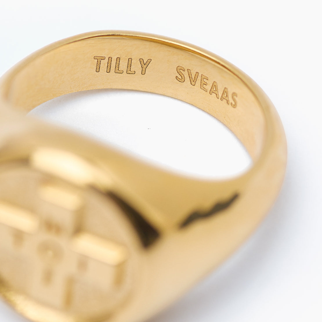 Gold ring with 'TILLY SVEAAS' engraving on a white background