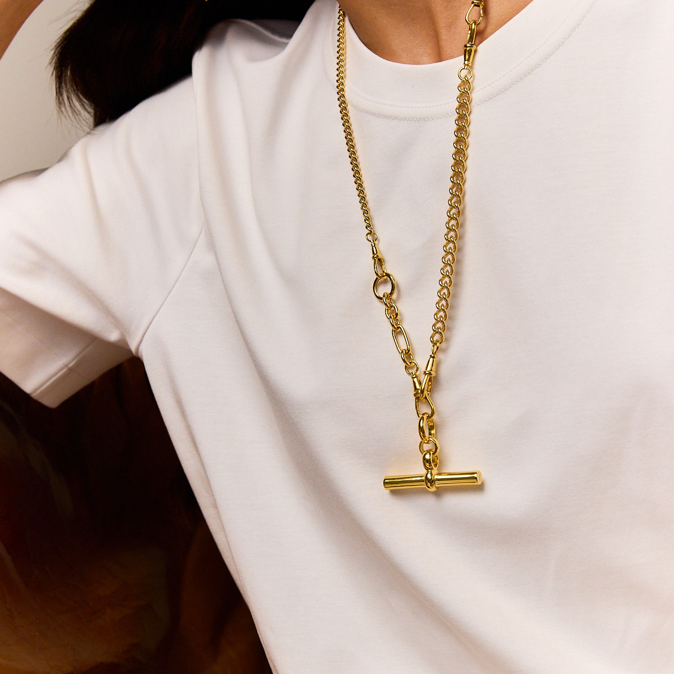 Gold-tone chain necklace with a T-bar pendant, worn long