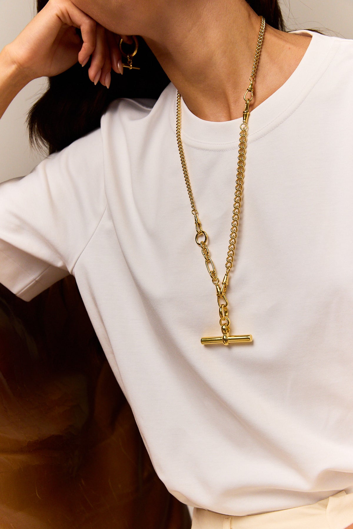 Gold-tone chain necklace with a T-bar pendant, worn long