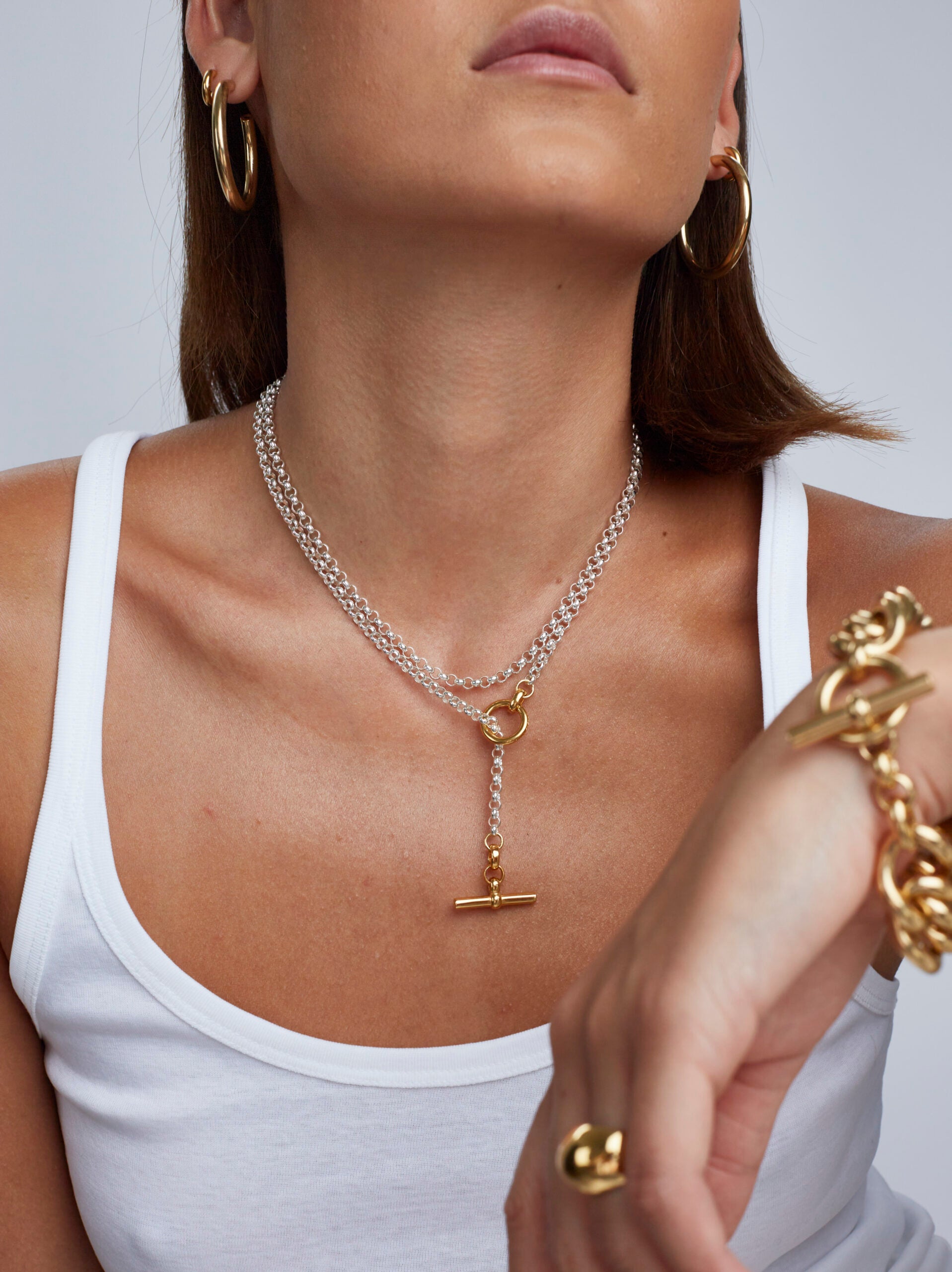 Close-up of a woman wearing gold jewelry including earrings, necklace, and bracelet.