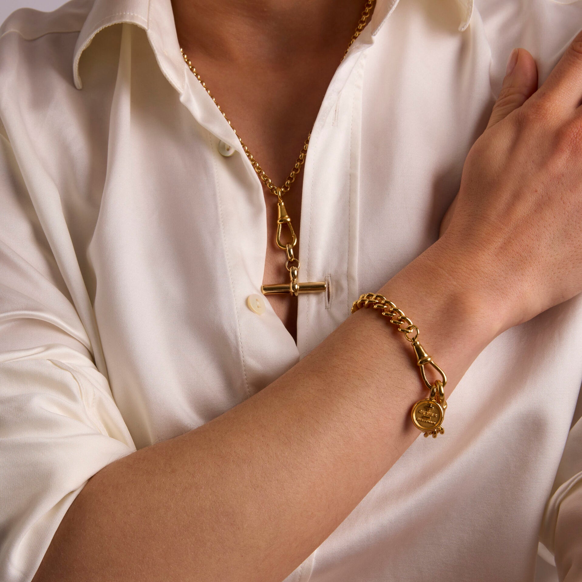 Gold mixed-link necklace set with round medallion pendant and bar charm, clasp visible