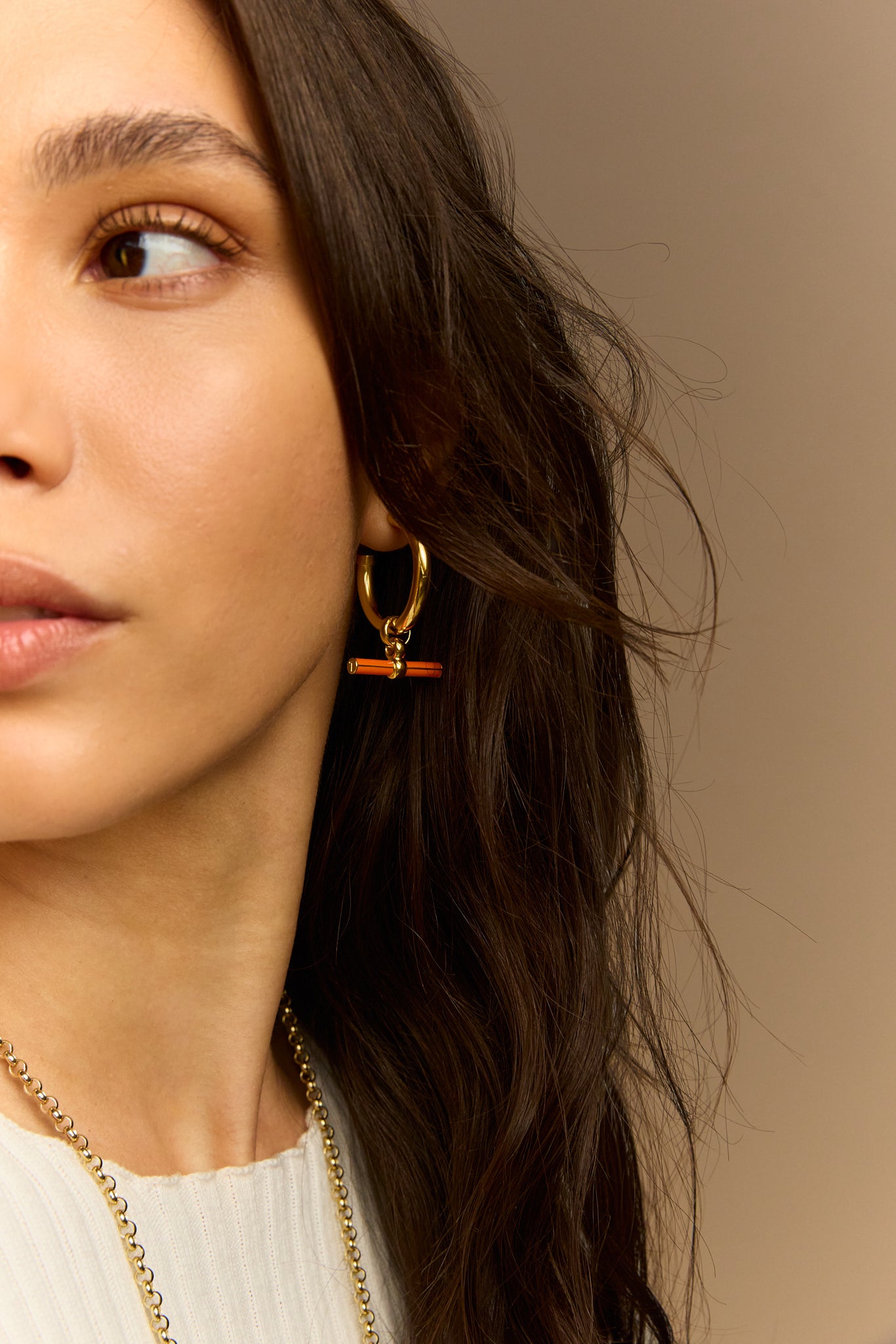 Gold hoop earrings with orange enamel T-bar detail and small charm