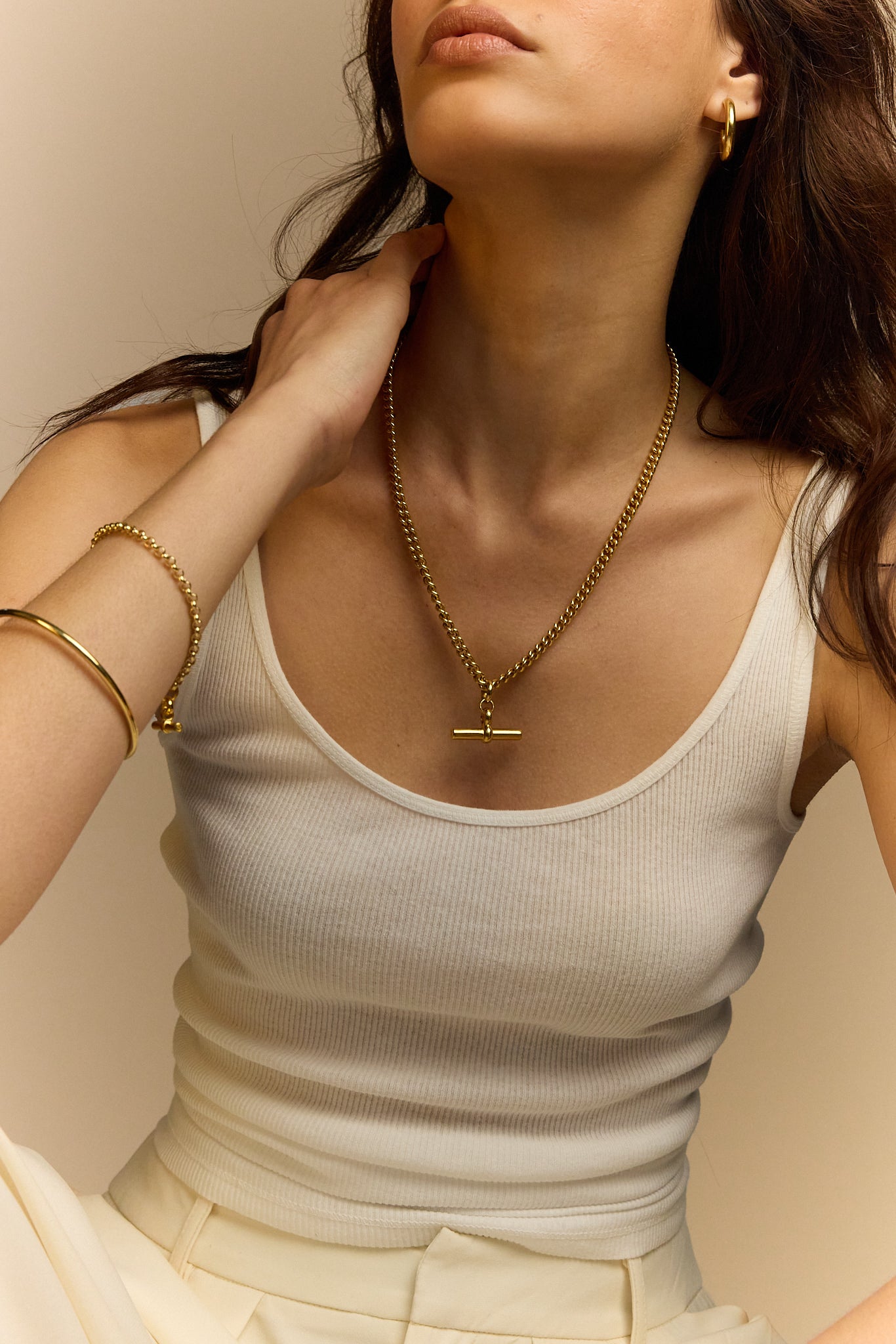 Gold curb link necklace with T-bar pendant, worn on a V-neck top