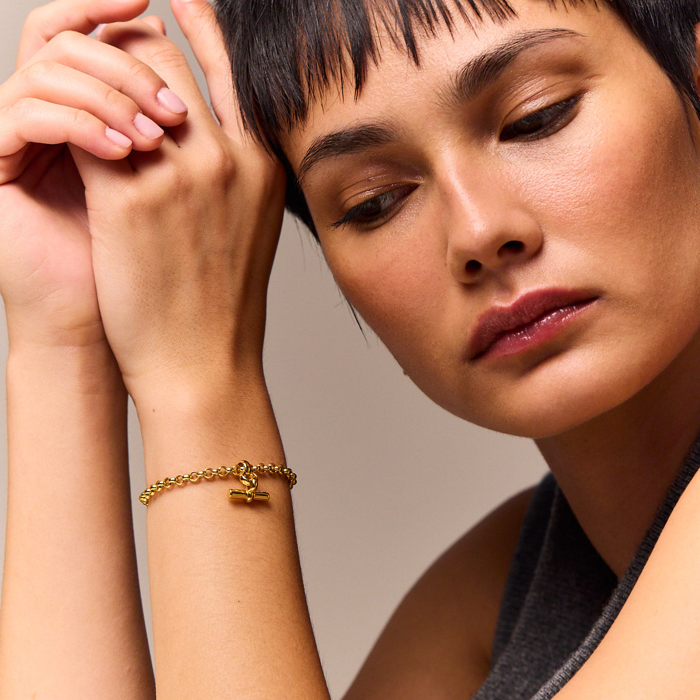 Gold chain bracelet with small T-bar charm on wrist