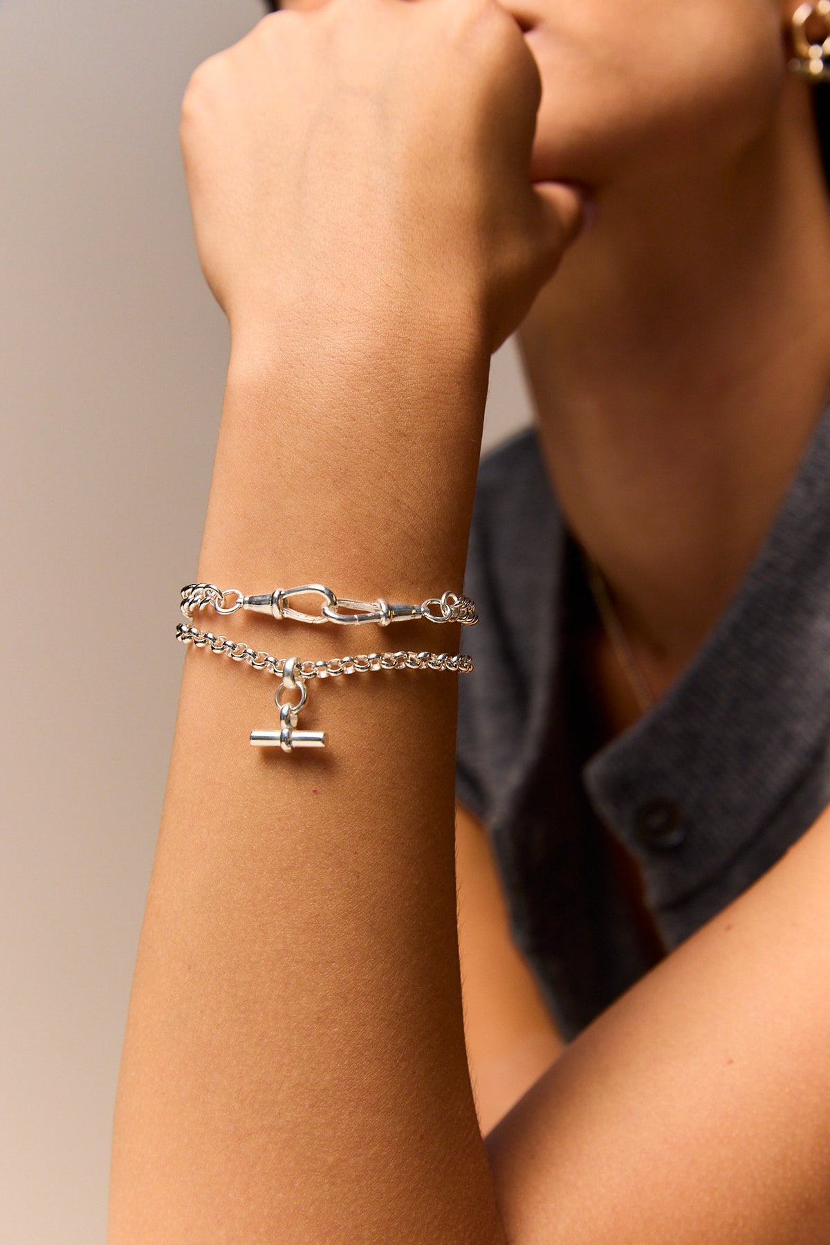 Slim silver curb bracelet worn on the wrist, shown with a lobster clasp.