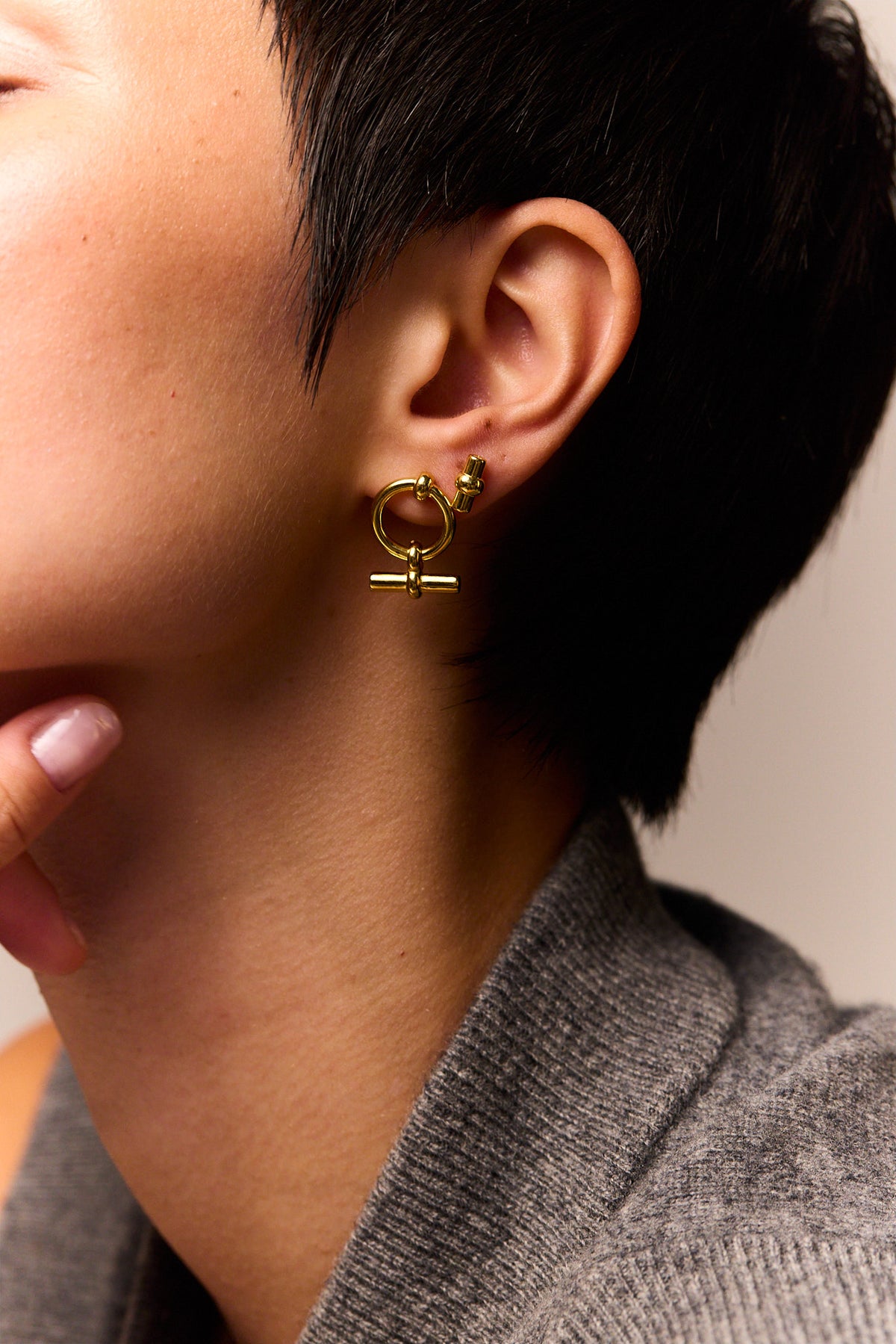 Gold T-bar eternity stud earrings with circular hoops, close-up on ear