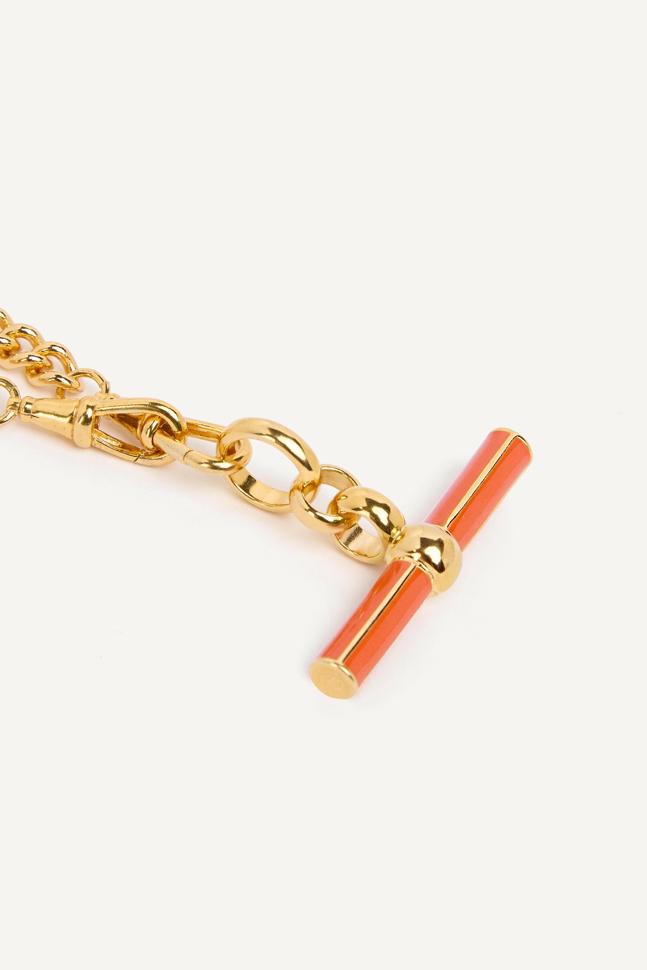 Gold chain necklace close-up: orange enamel T-bar pendant