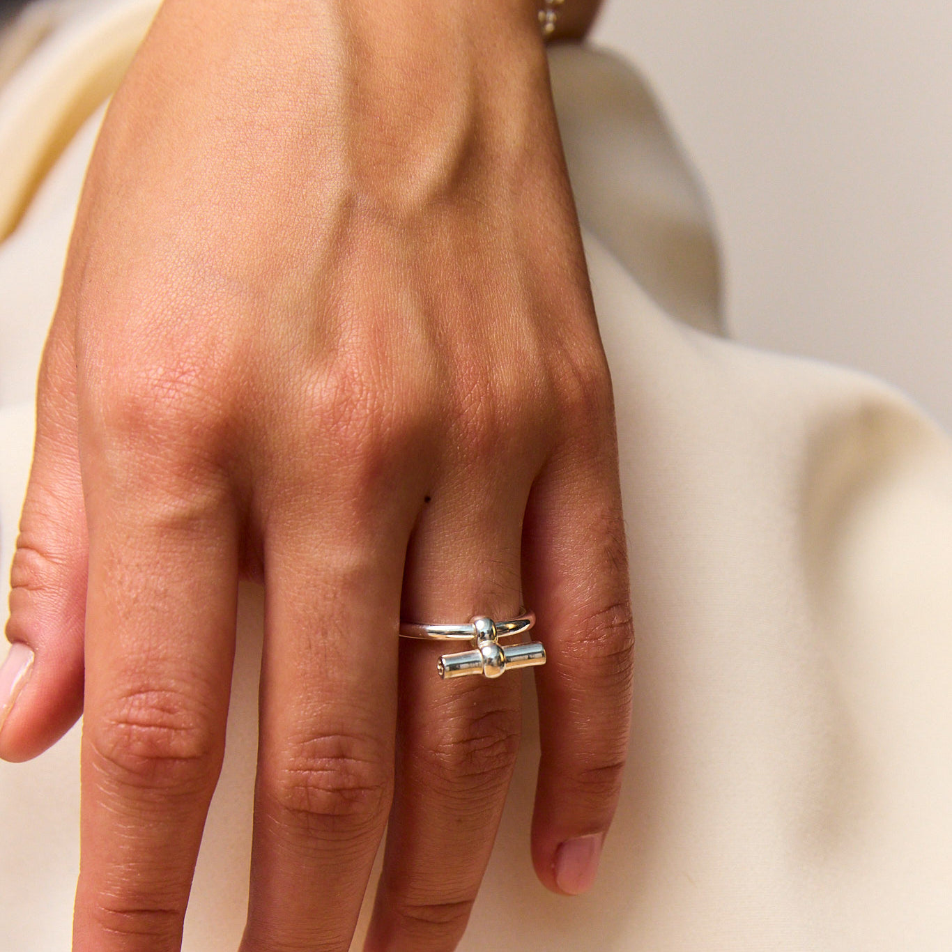 Silver T-bar eternity ring on finger, minimalist band with small top bar.