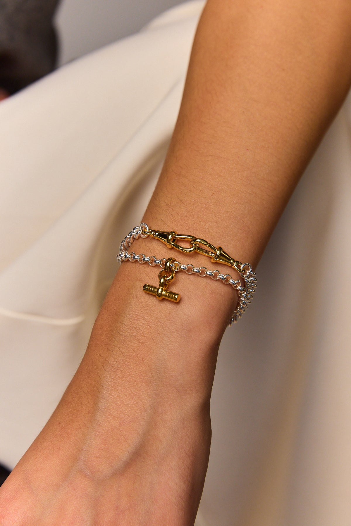 Silver and gold-tone curb bracelet worn on the wrist