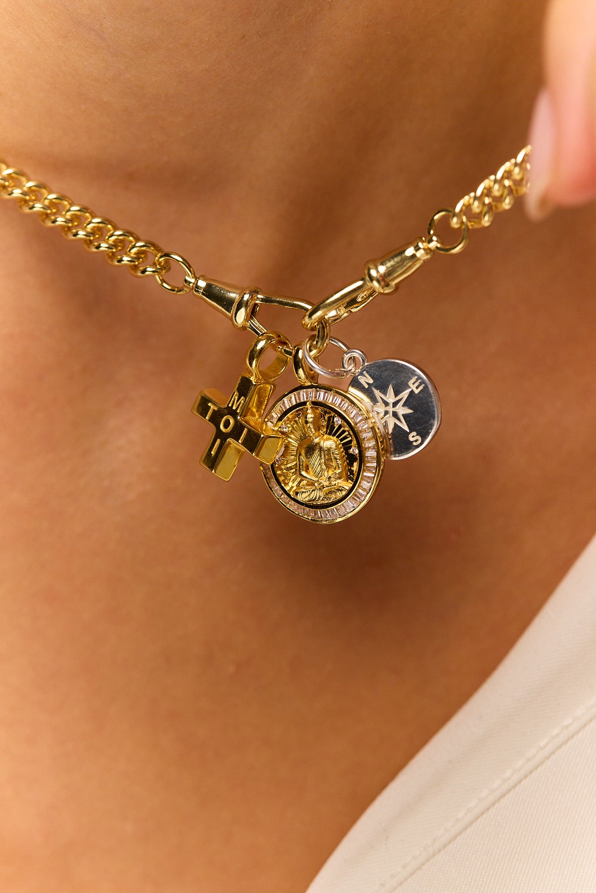 Gold-tone charm necklace with compass and cross pendants on a chain