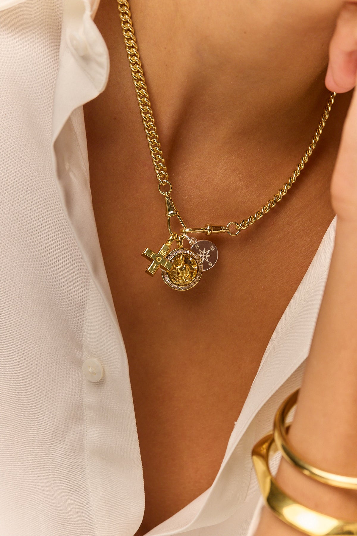 Gold-tone charm pendant necklace with circular compass, cross, and star charms