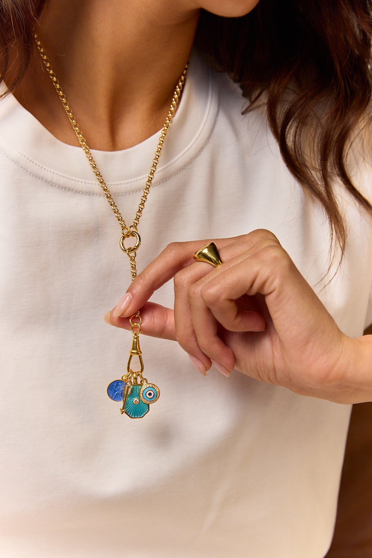 Gold-tone chain necklace with blue evil-eye charm pendant, shown with close hand detail