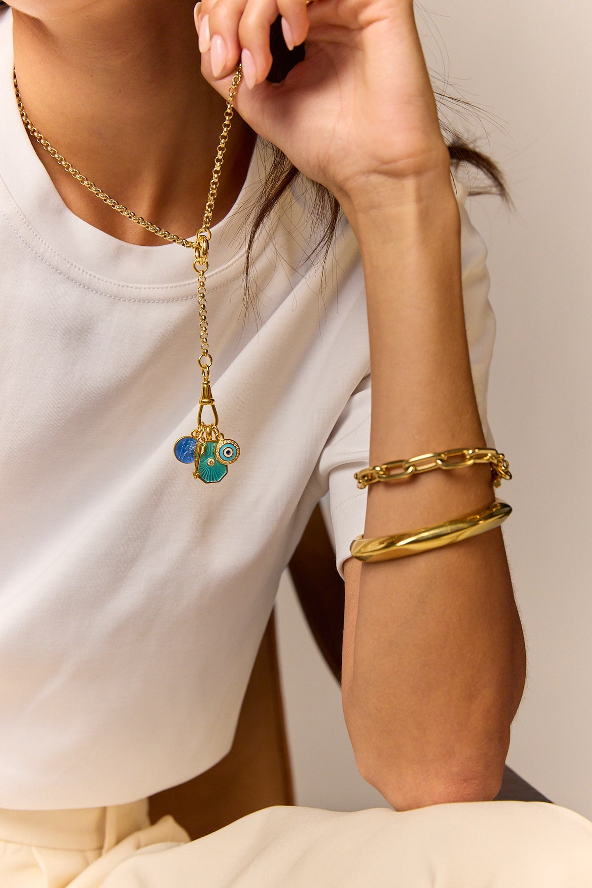 Gold-tone necklace with blue evil-eye pendant and matching gold chain bracelets on wrist