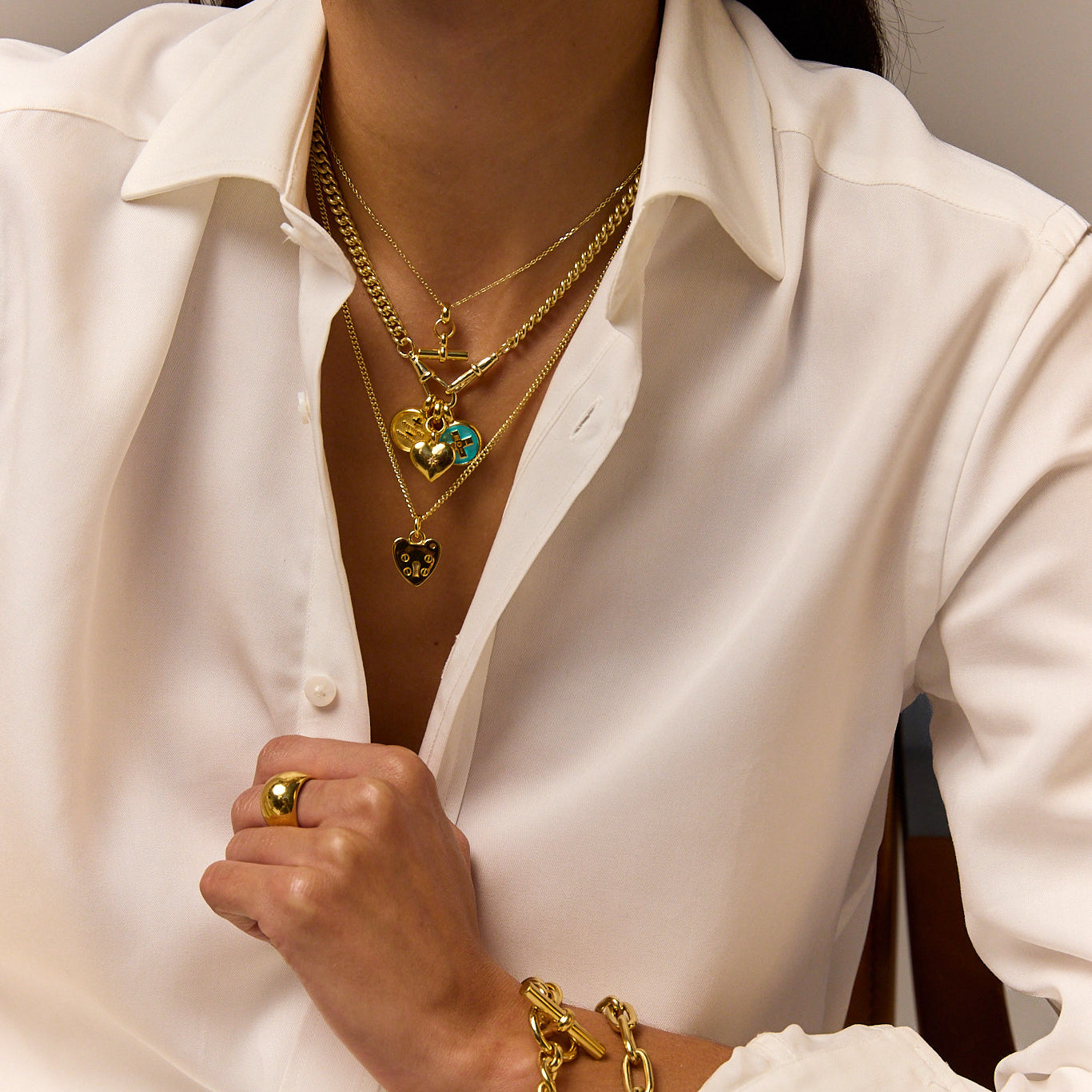 Gold heart pendant necklace layered with small round charm and dangling beads