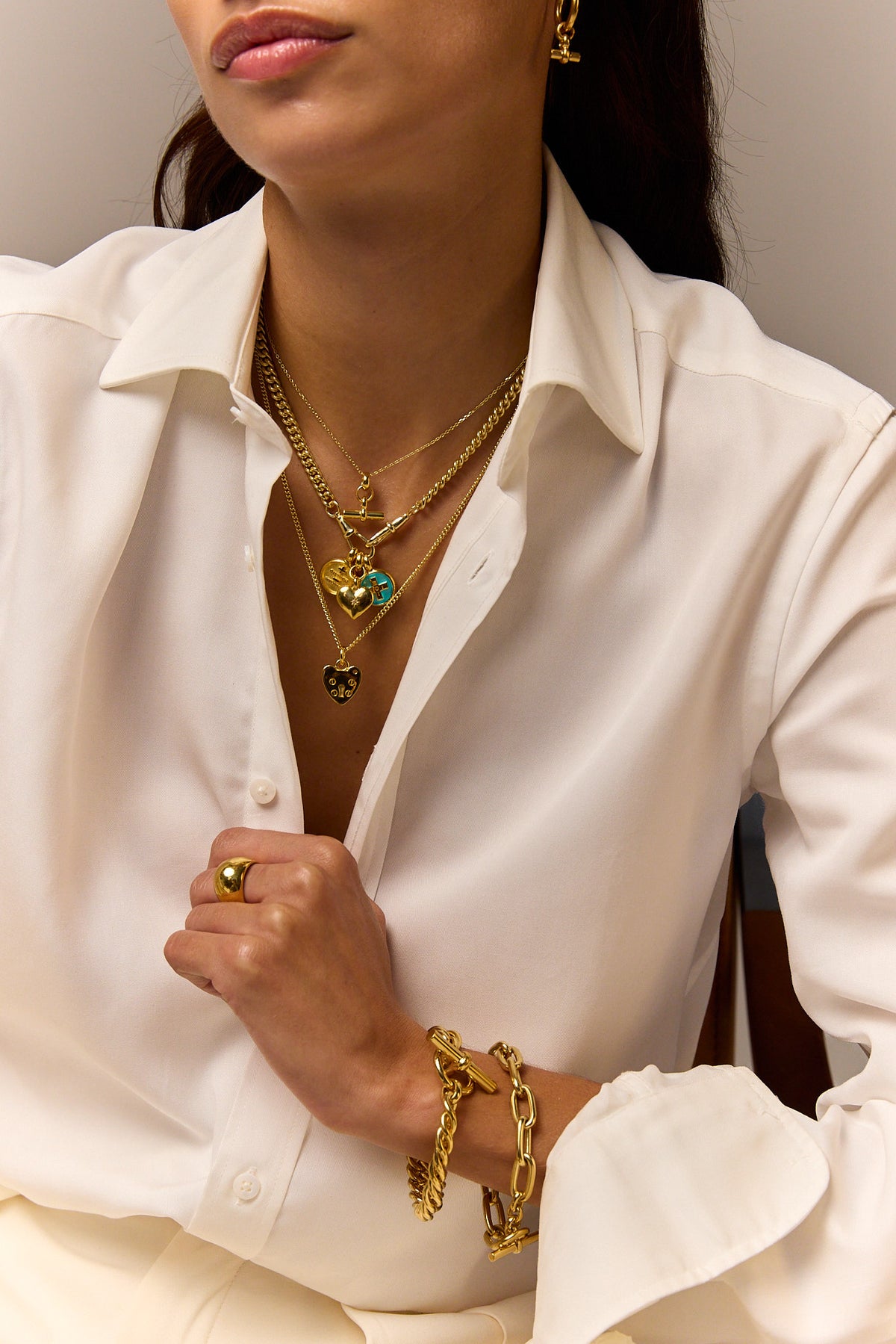 Gold heart pendant necklace layered with small round charm and dangling beads