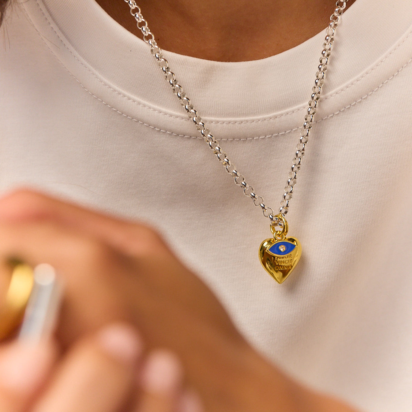 Silver chain necklace with gold heart charm and blue eye pendant close-up