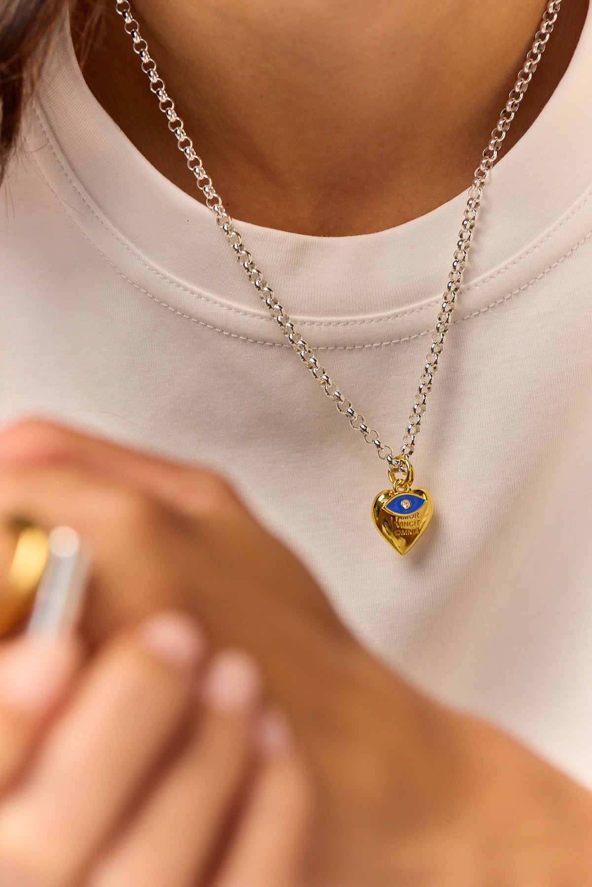 Silver chain necklace with gold heart charm and blue eye pendant close-up