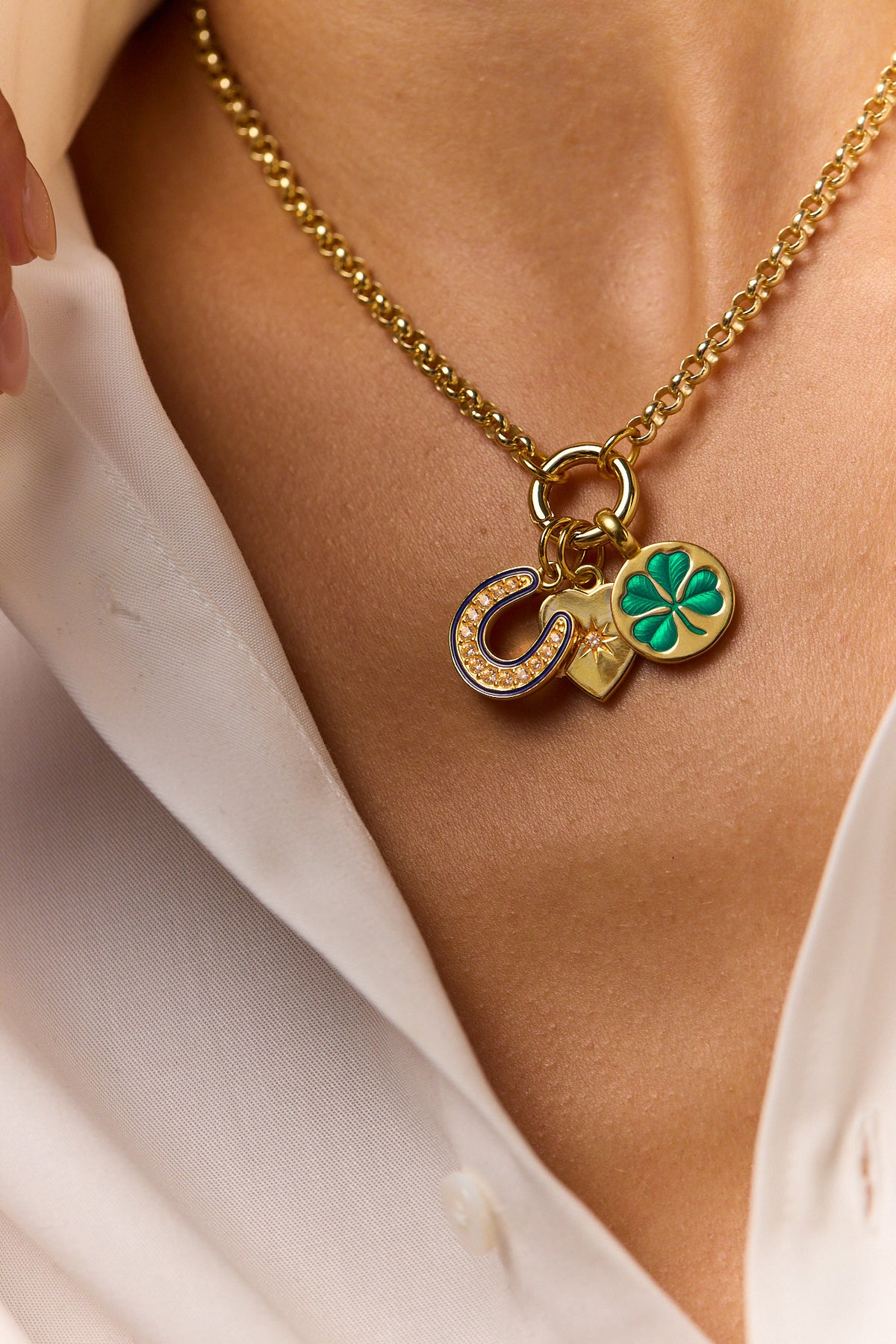 Gold-tone charm necklace with heart, clover, and crystal accents; green enamel pendant