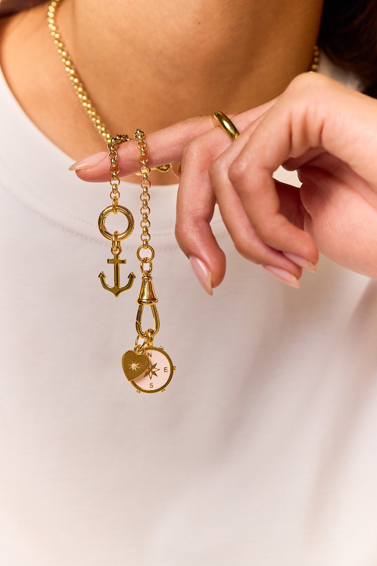 Gold charm necklace with anchor, cross charm, and compass face, clasp detail