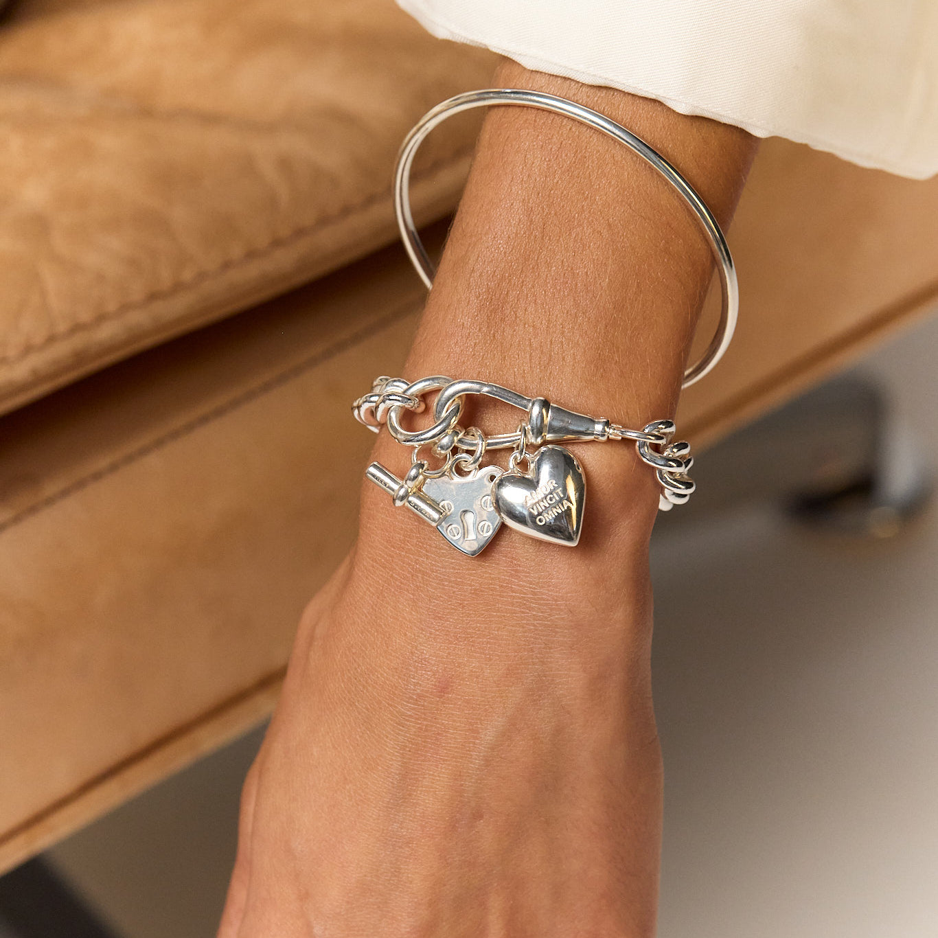 Silver chain bracelet with heart and padlock charms on wrist