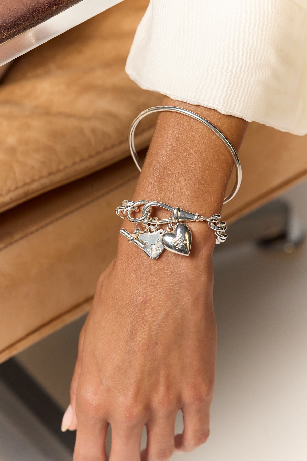 Silver chain bracelet with heart and padlock charms on wrist