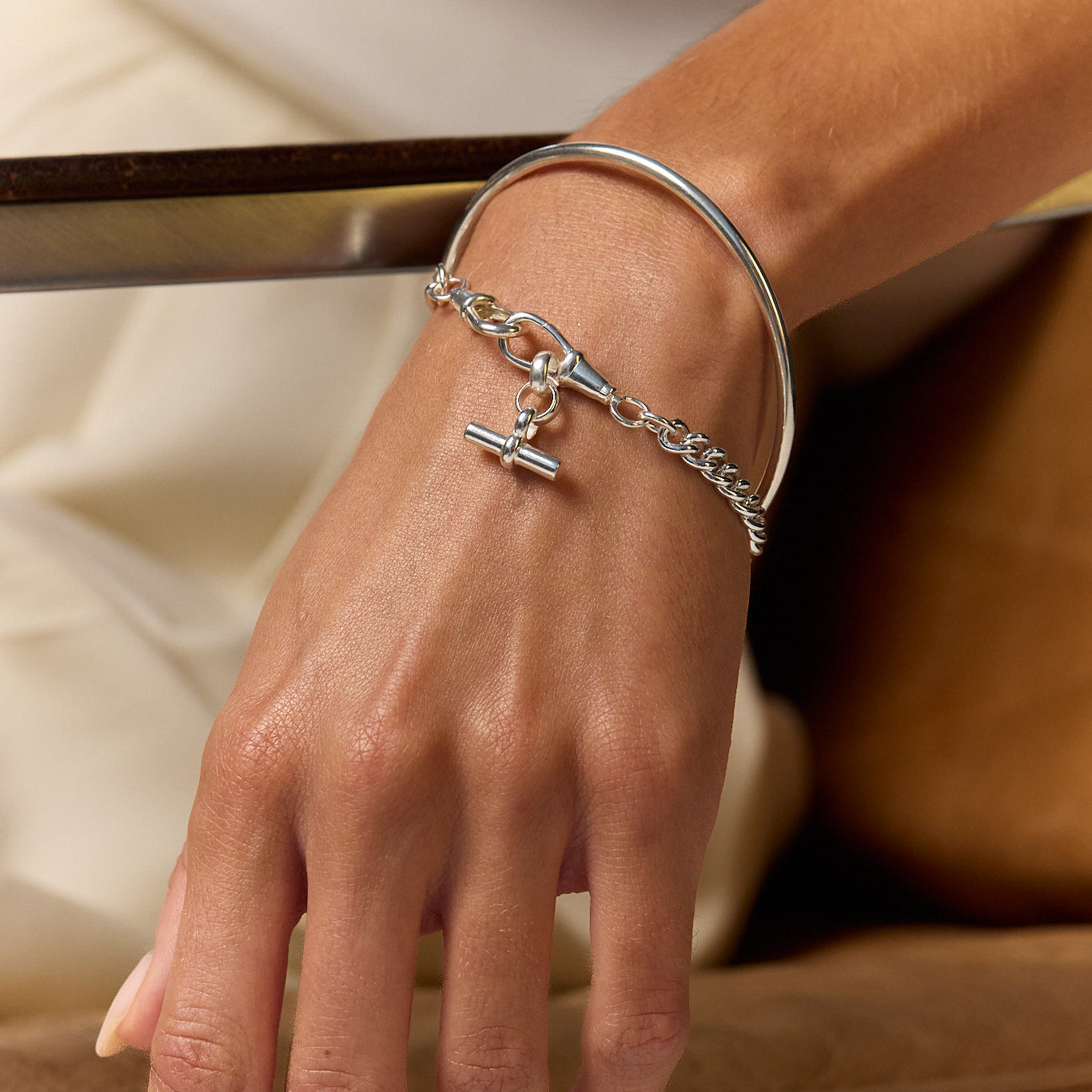 Silver chain bracelet with cross and blue gem charm on hand