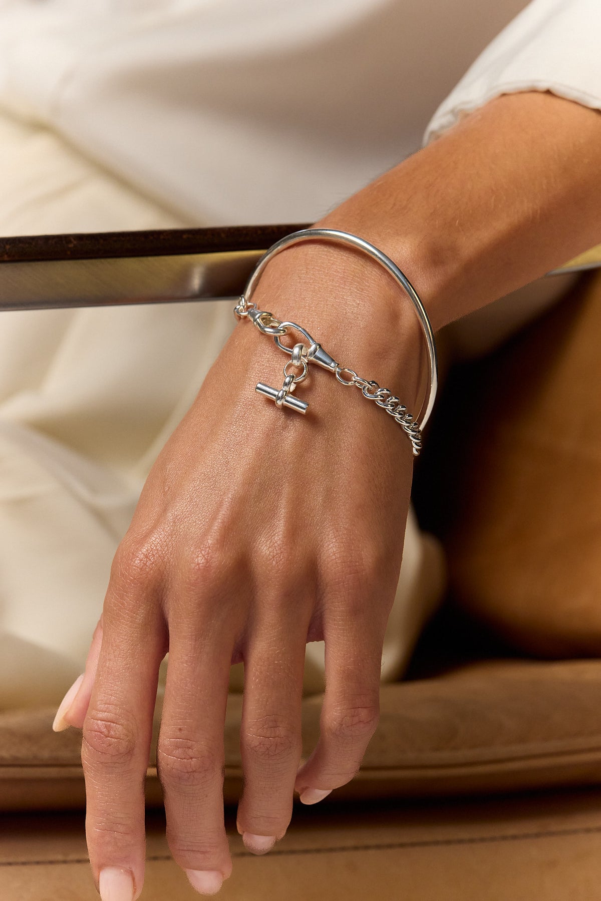 Silver chain bracelet with cross and blue gem charm on hand