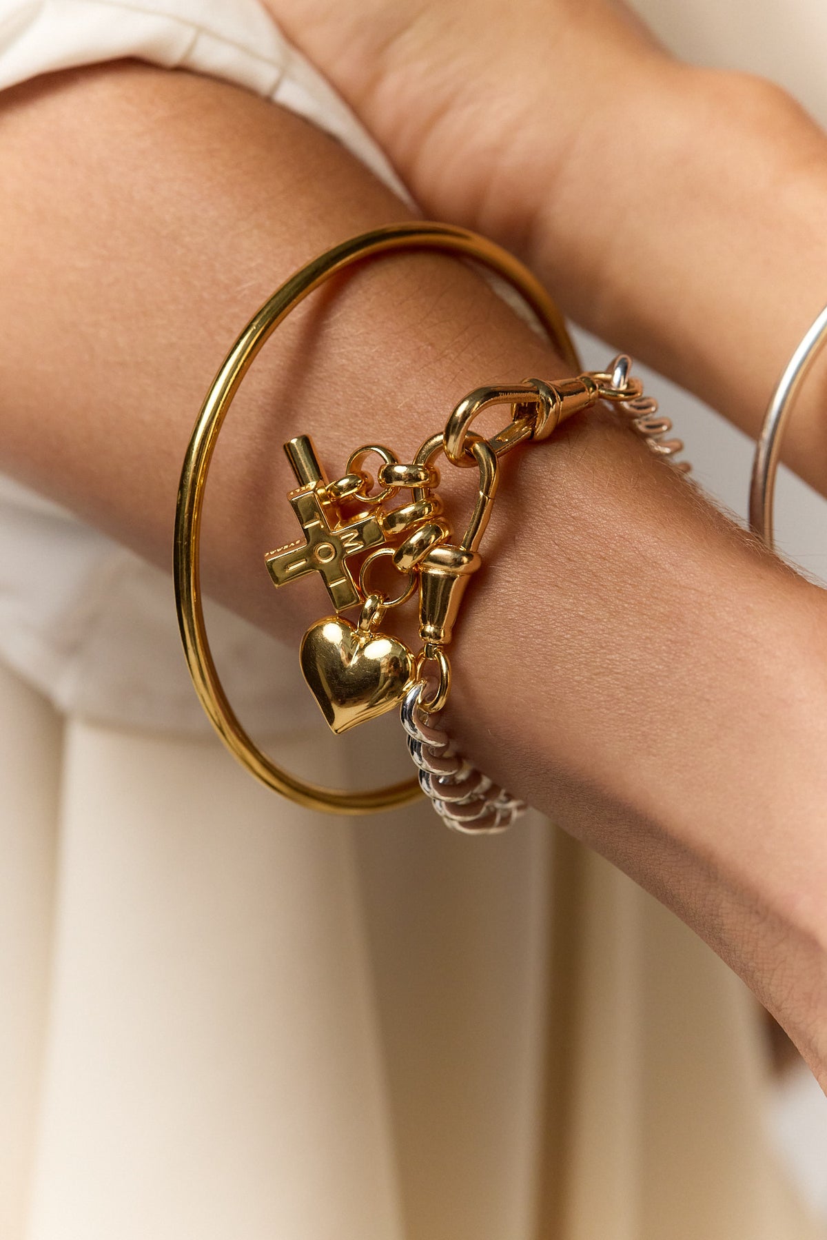 Gold bangle bracelet with silver chain and gold heart lock charms