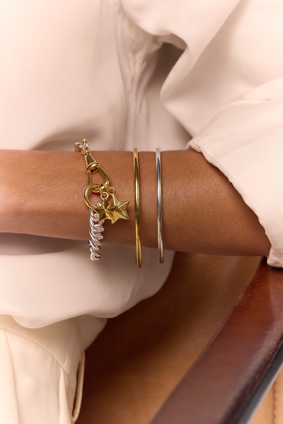 Star charm bracelet on wrist with gold and silver bangles